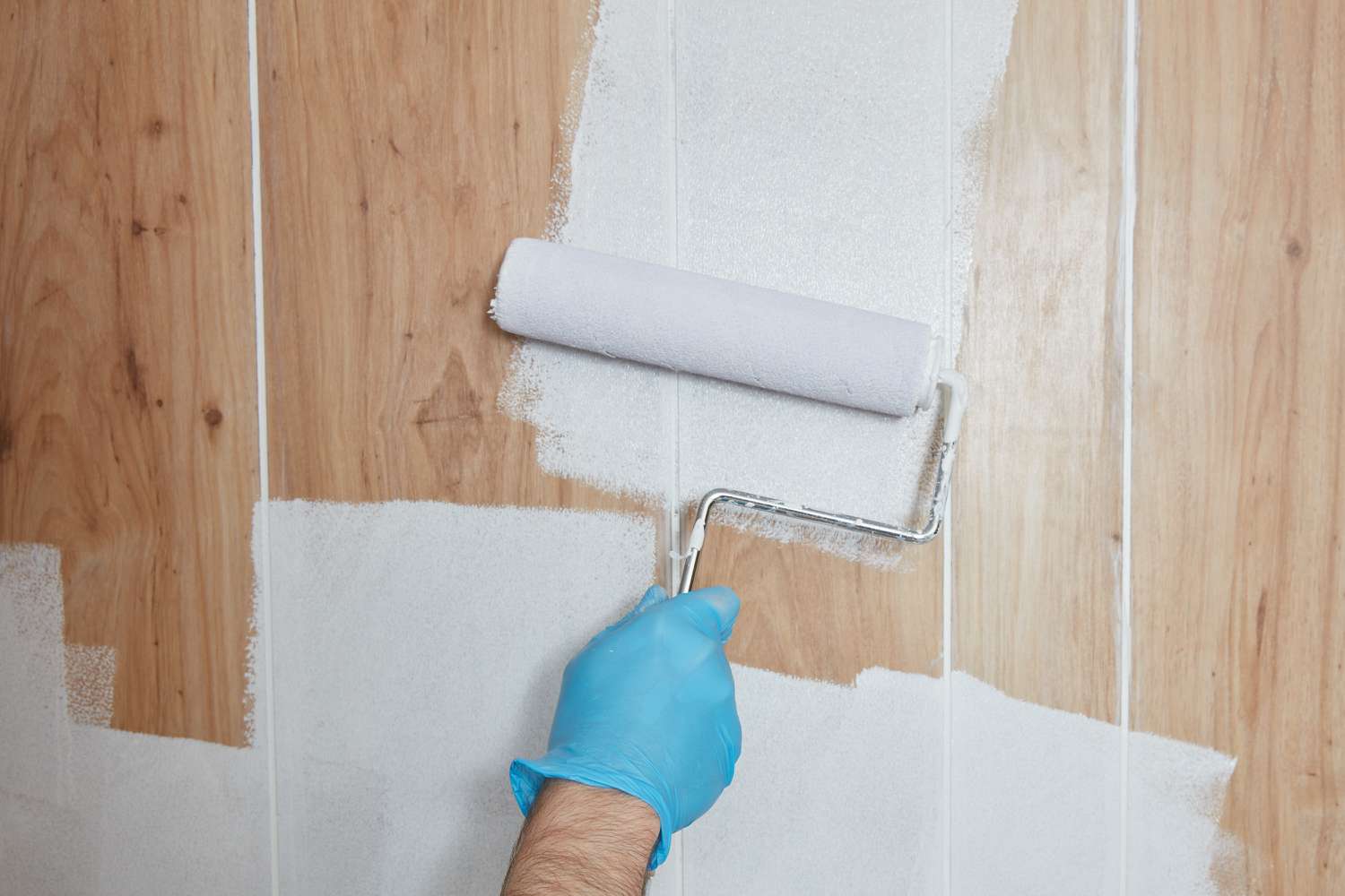 Paneles de madera siendo pintados con pintura blanca sobre rodillo