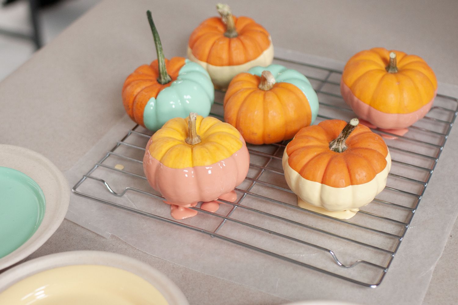 Pumpkins dipped in paint sitting on metal try to dry