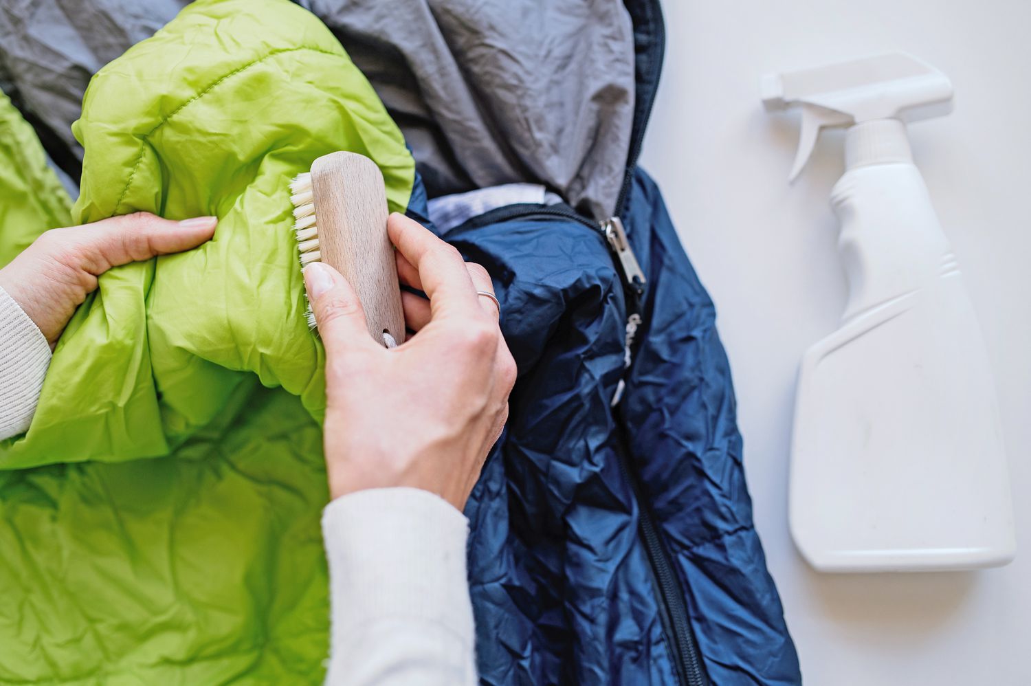 Flecken aus synthetischem Schlafsack mit Fleckenentferner auf Enzymbasis und Scheuerbürste entfernen