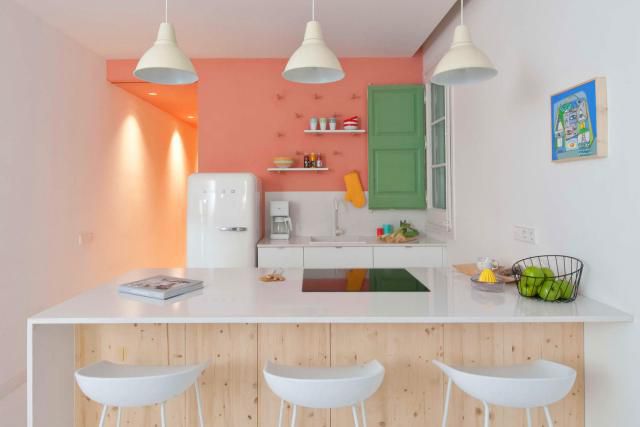 Encimeras blancas con una pared de acento color salmón en una cocina blanca.