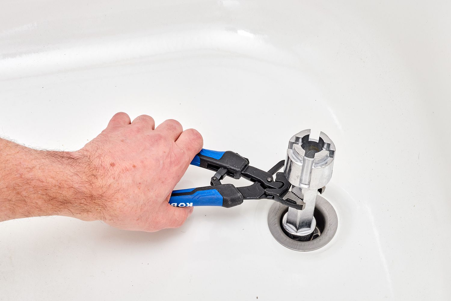 Adjustable wrench pulling out old drain fitting from bathtub
