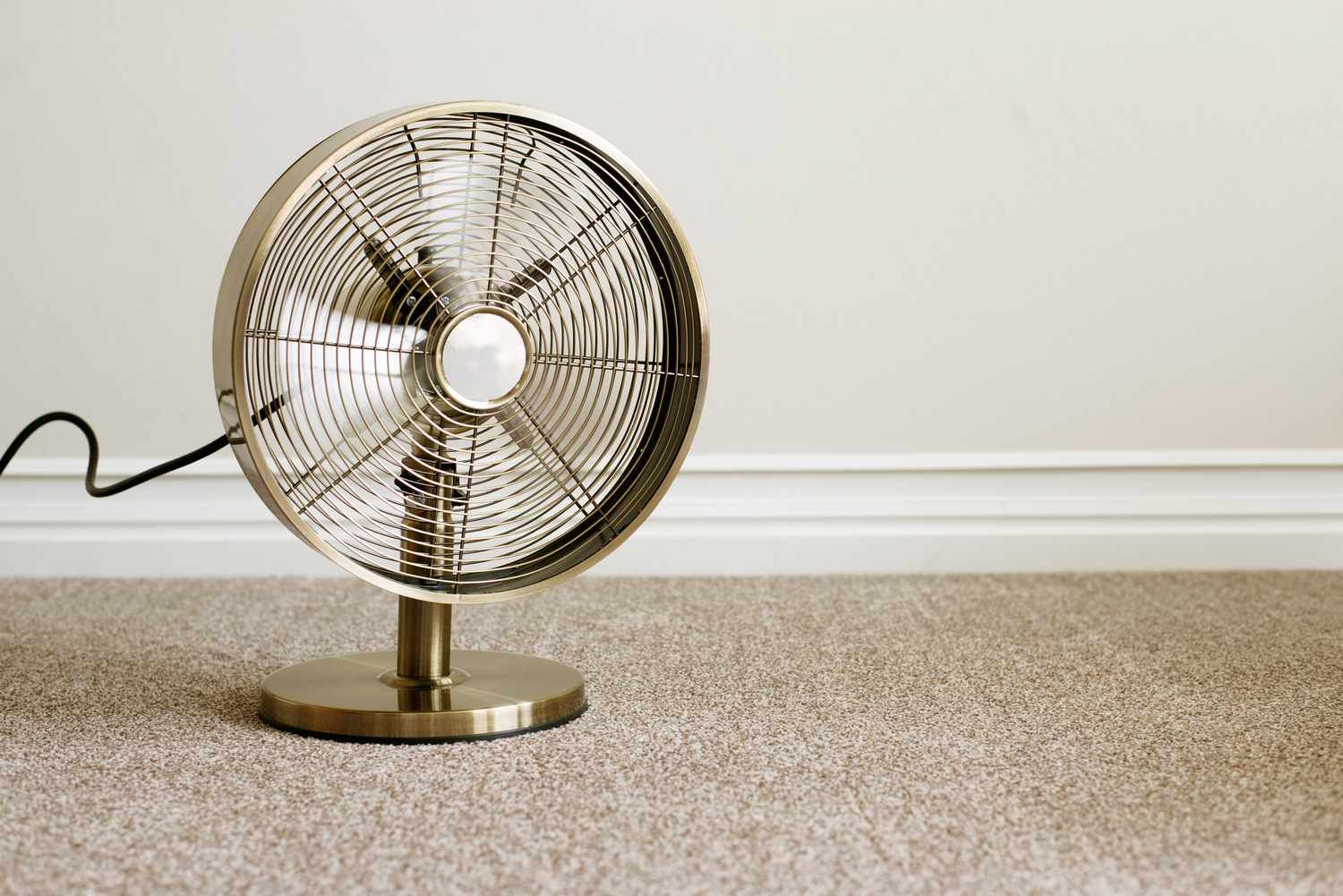 Brass oscillating fan increasing airflow while carpet dries