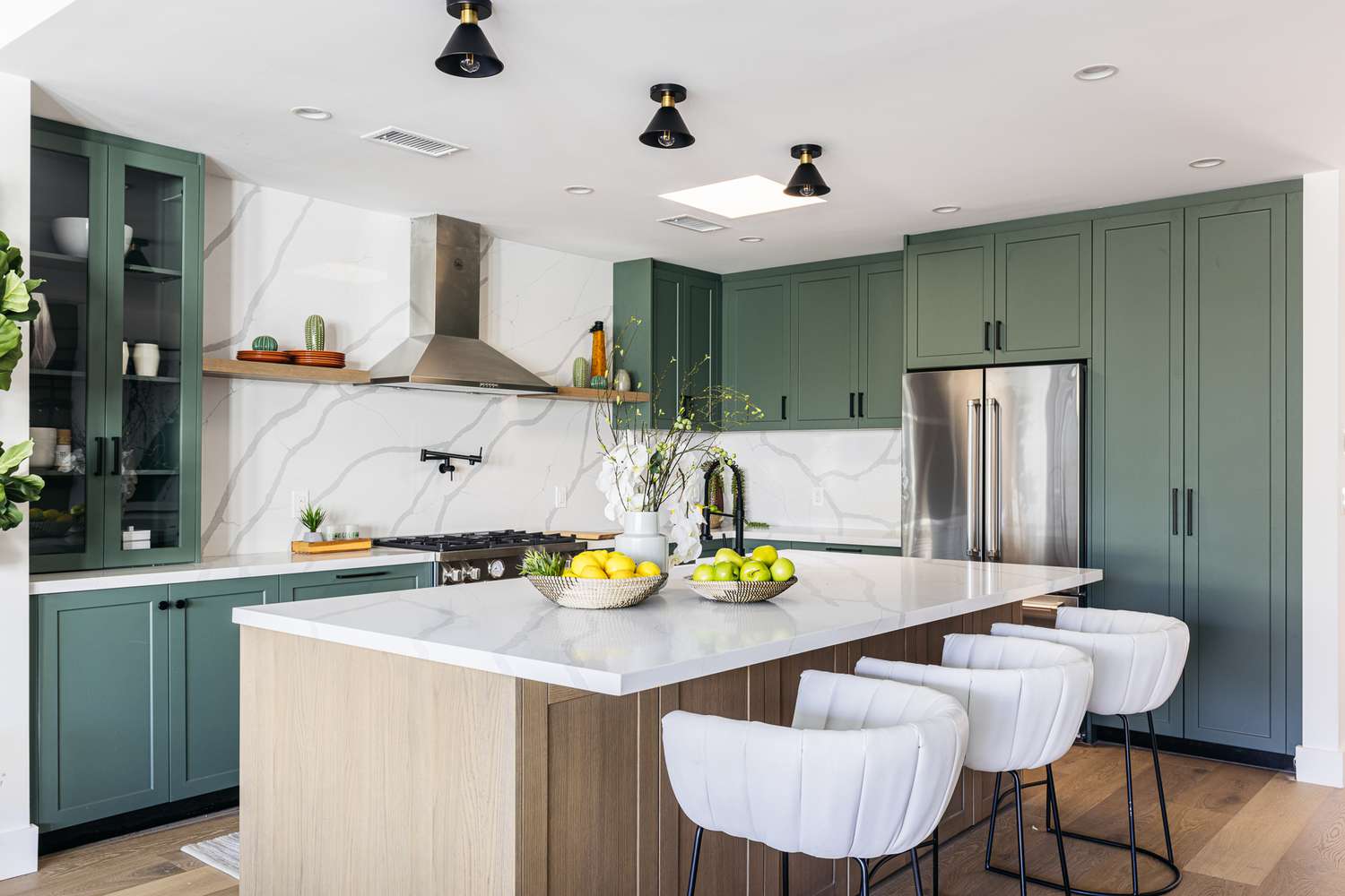 Ilha de cozinha com bancada de mármore cercada por armários verdes