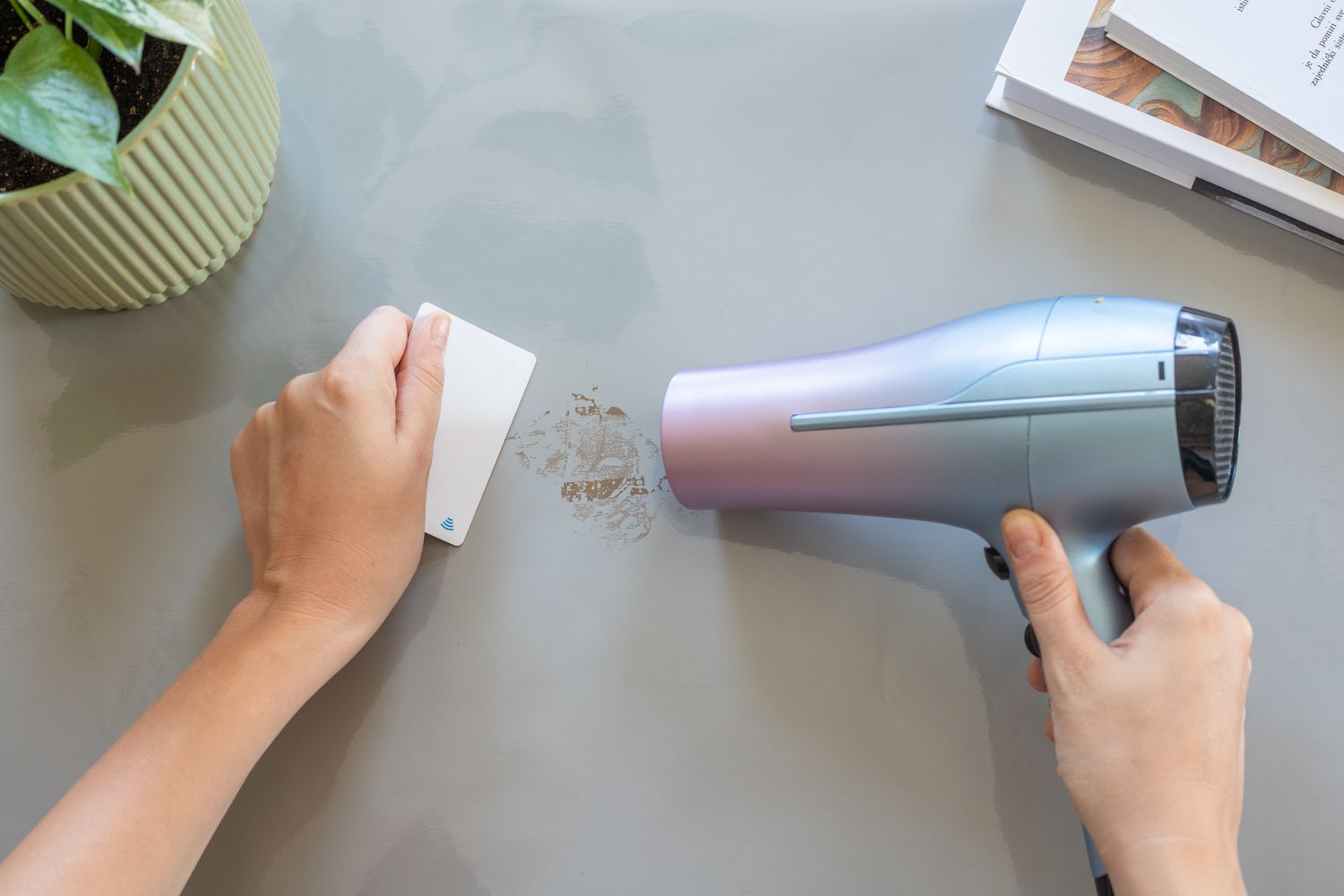 Blow dryer adding heat to tape residue on painted surface and scraped with credit card