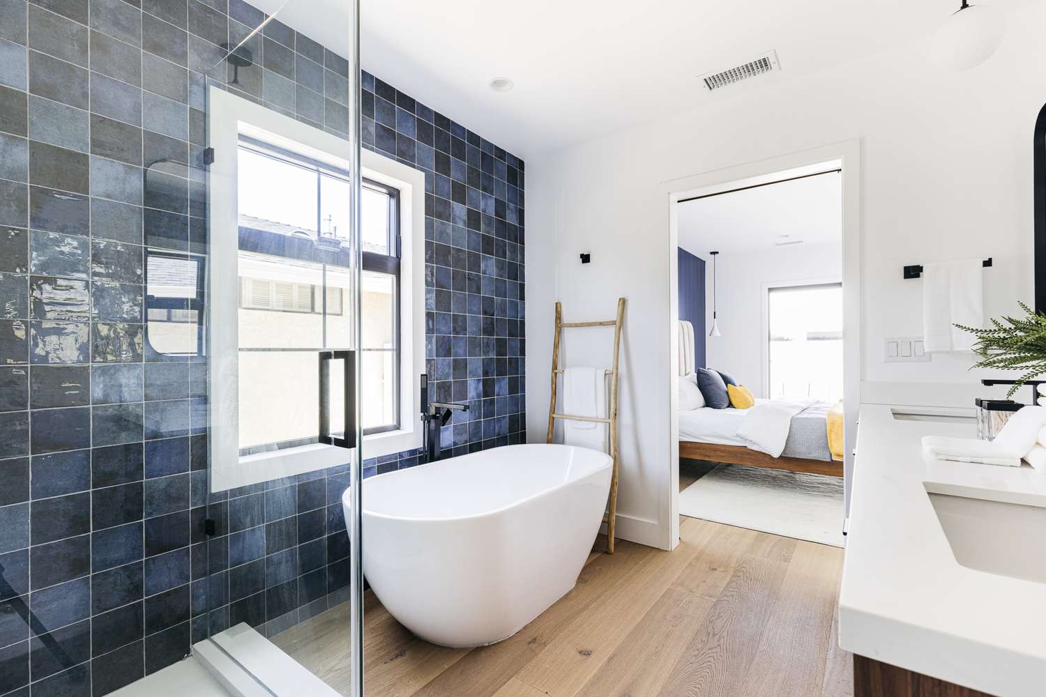 Freestanding tub next to blue-tiled wall in spa-like bathroom