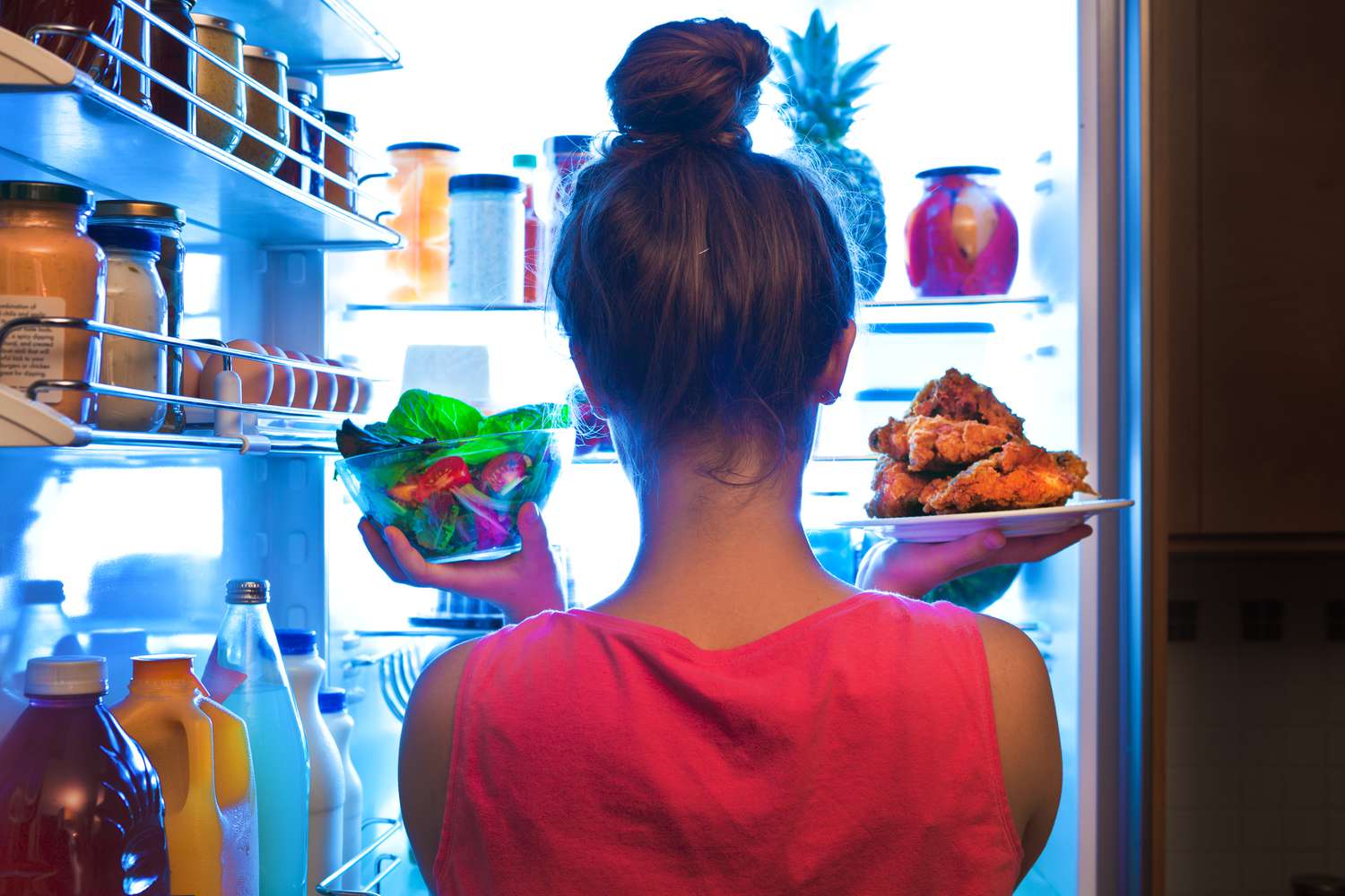 Woman pulling unwrapped food from the fridge.
