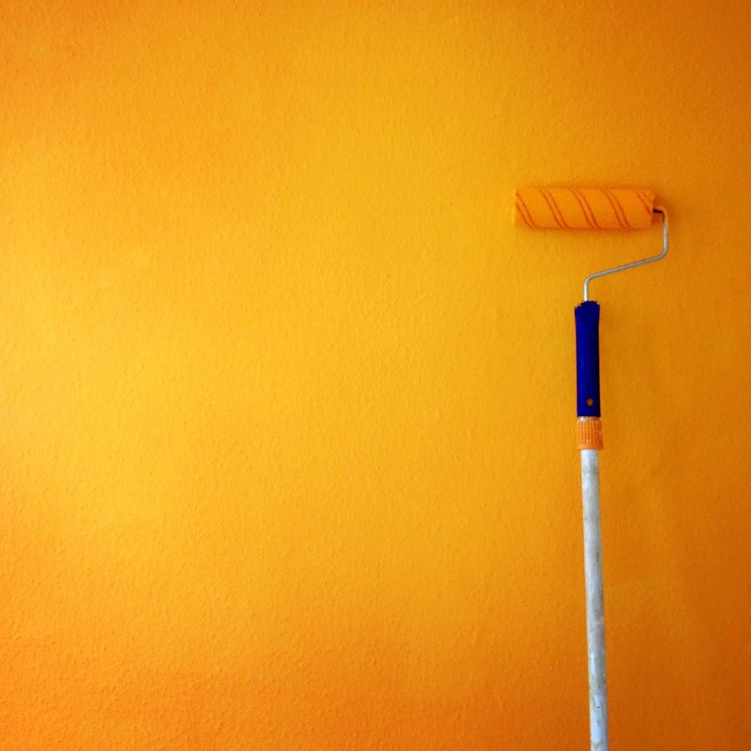 Rouleau de peinture sur mur jaune