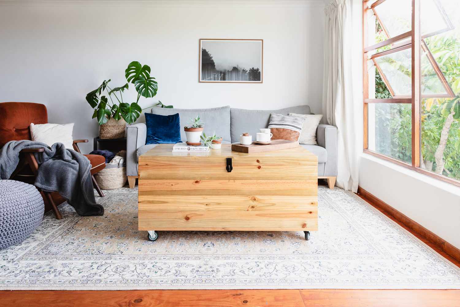 Light colored area rug in decorated living space under wooden trunk with wheels