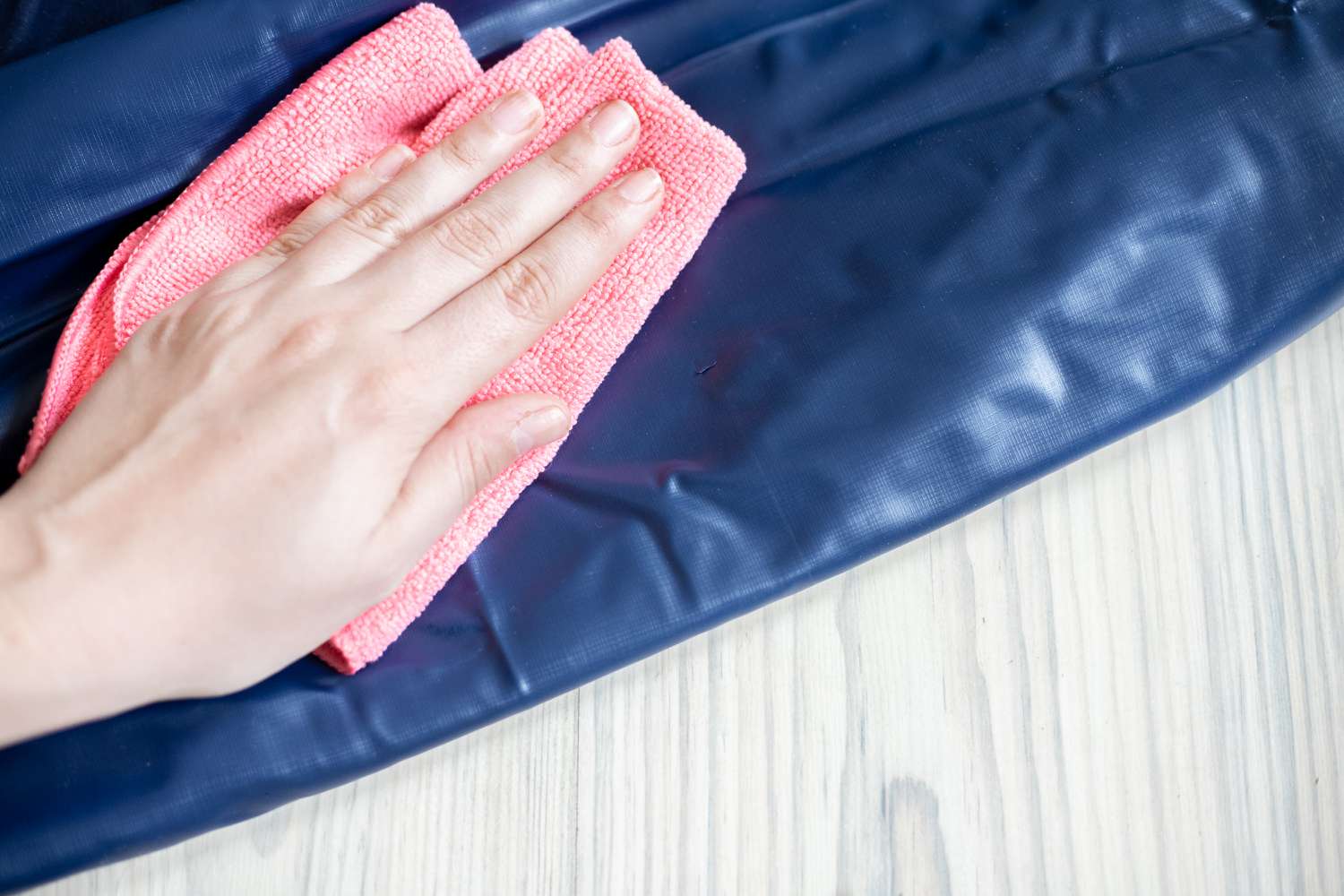Colchón de aire azul limpiado con un paño de microfibra rosa humedecido con alcohol de quemar