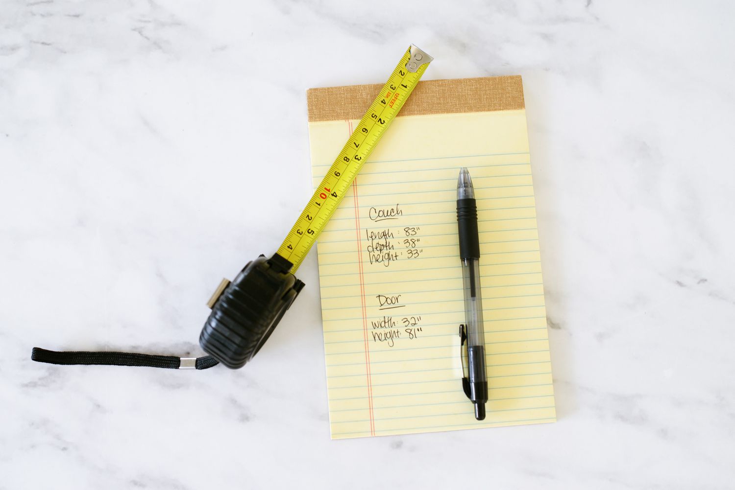 Medidas escritas em um bloco de notas amarelo com caneta e fita métrica