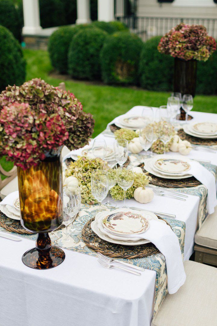 Mesa ao ar livre com pratos de outono, abóboras brancas e hortênsias secas