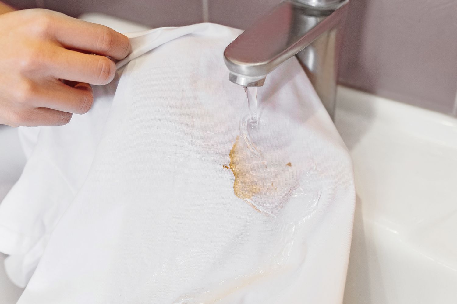 Camisa manchada de salsa de soja aclarada bajo el chorro de agua fría