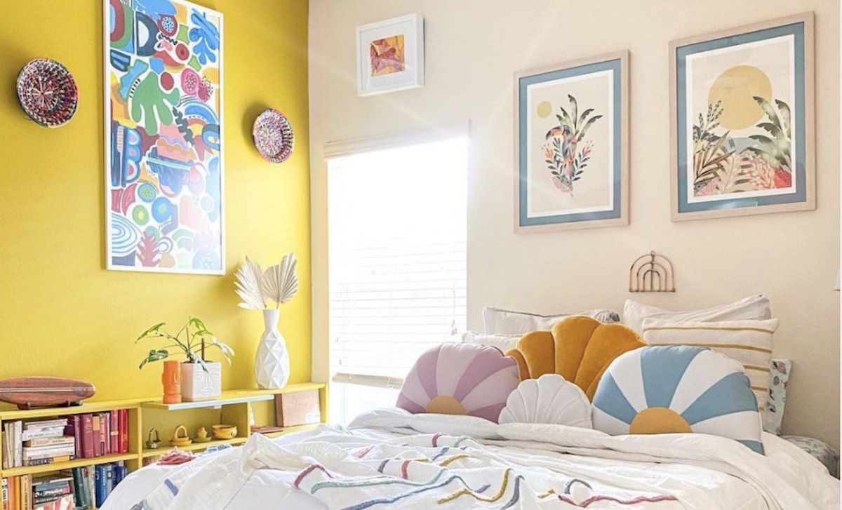 bedroom with bright yellow accent wall, prints hanging on wall, 