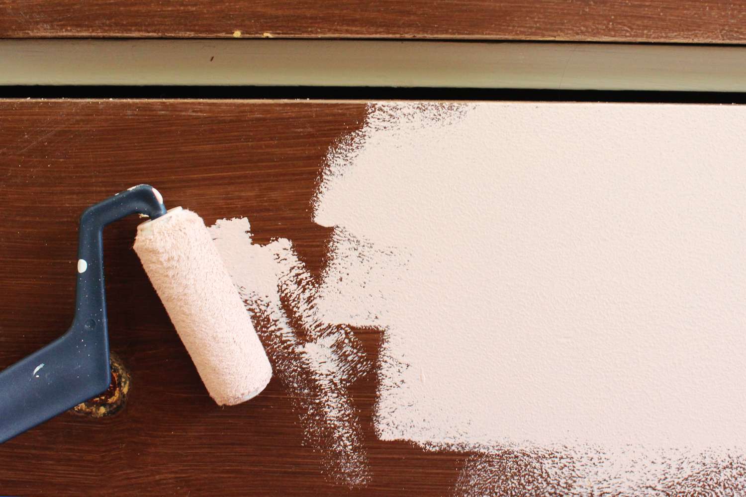 Using a roller brush with chalk paint on a dresser