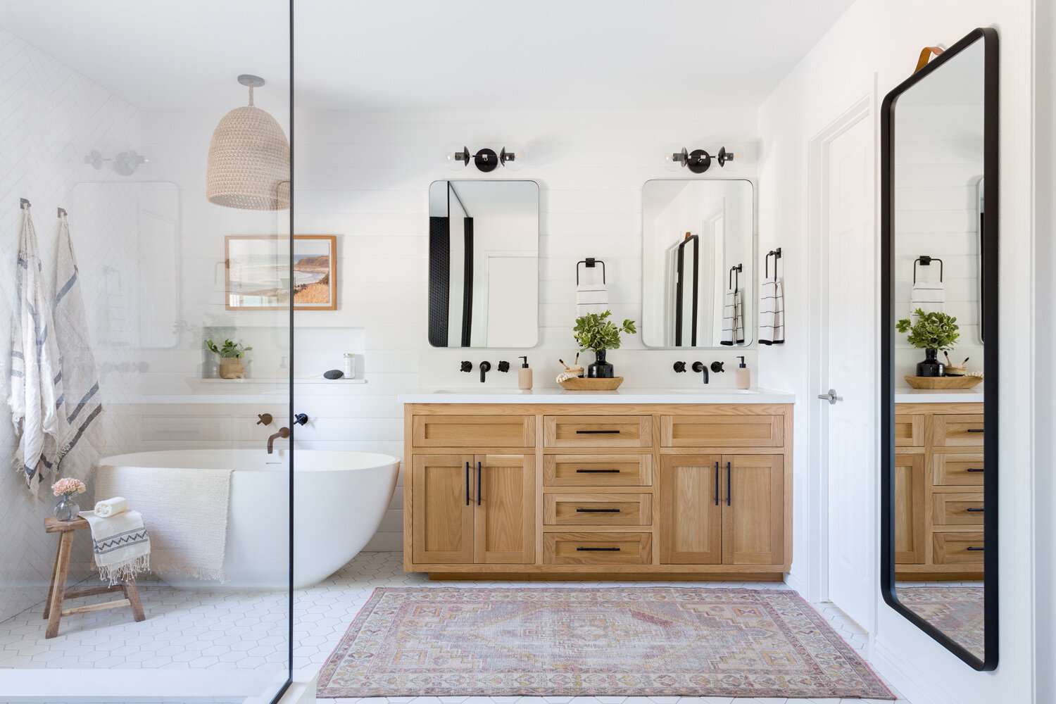 Ein großes weißes Badezimmer mit einem verzierten Teppich und einem Holz-Waschtisch