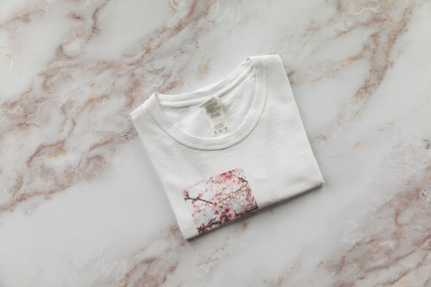 T-shirt blanc avec image imprimée en rouge plié proprement sur une surface marbrée blanche