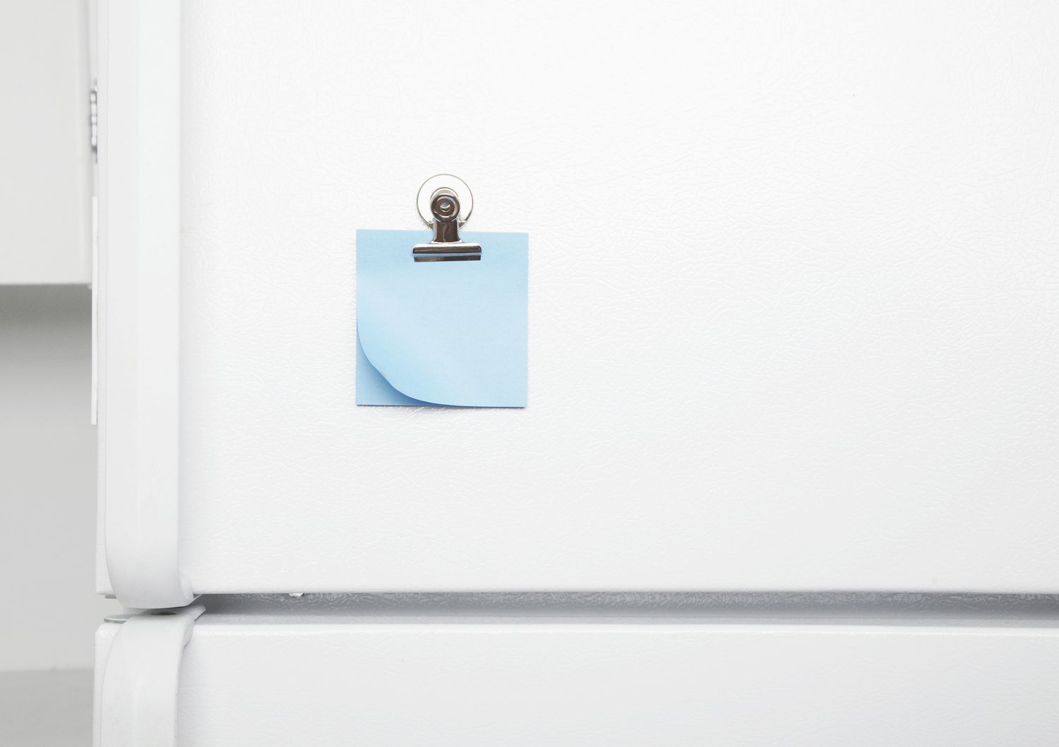 Exterior da porta da geladeira com nota adesiva azul.