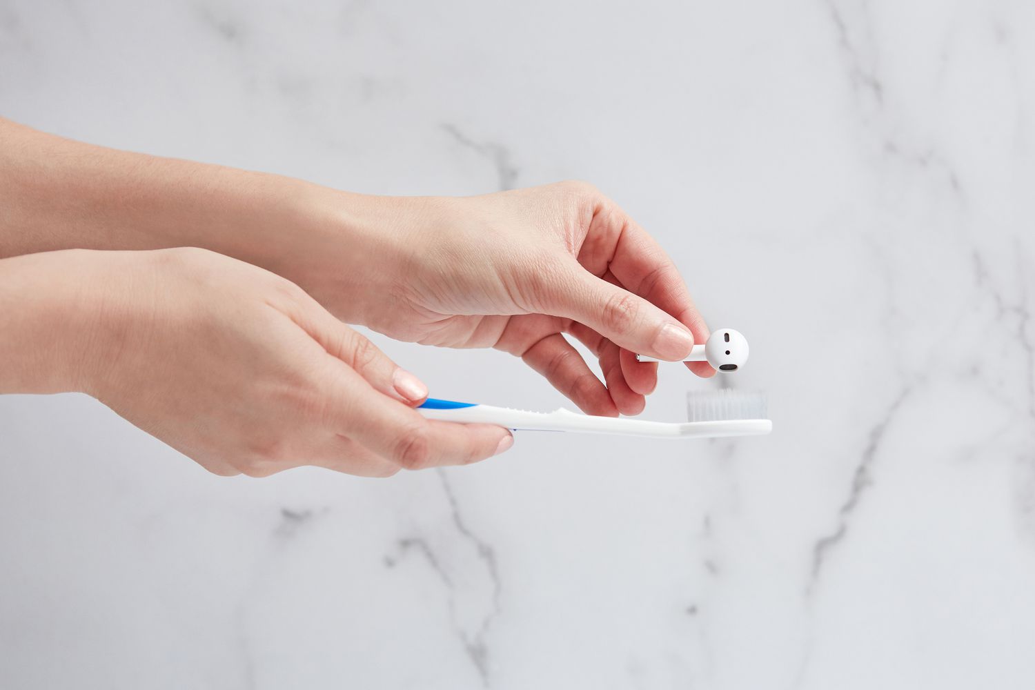 Person reinigt Ohrstöpsel mit einer Zahnbürste