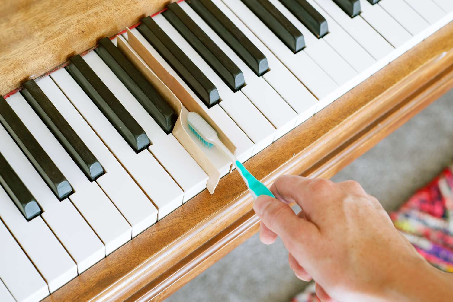 Usando un cepillo de dientes húmedo para fregar las teclas de marfil del piano