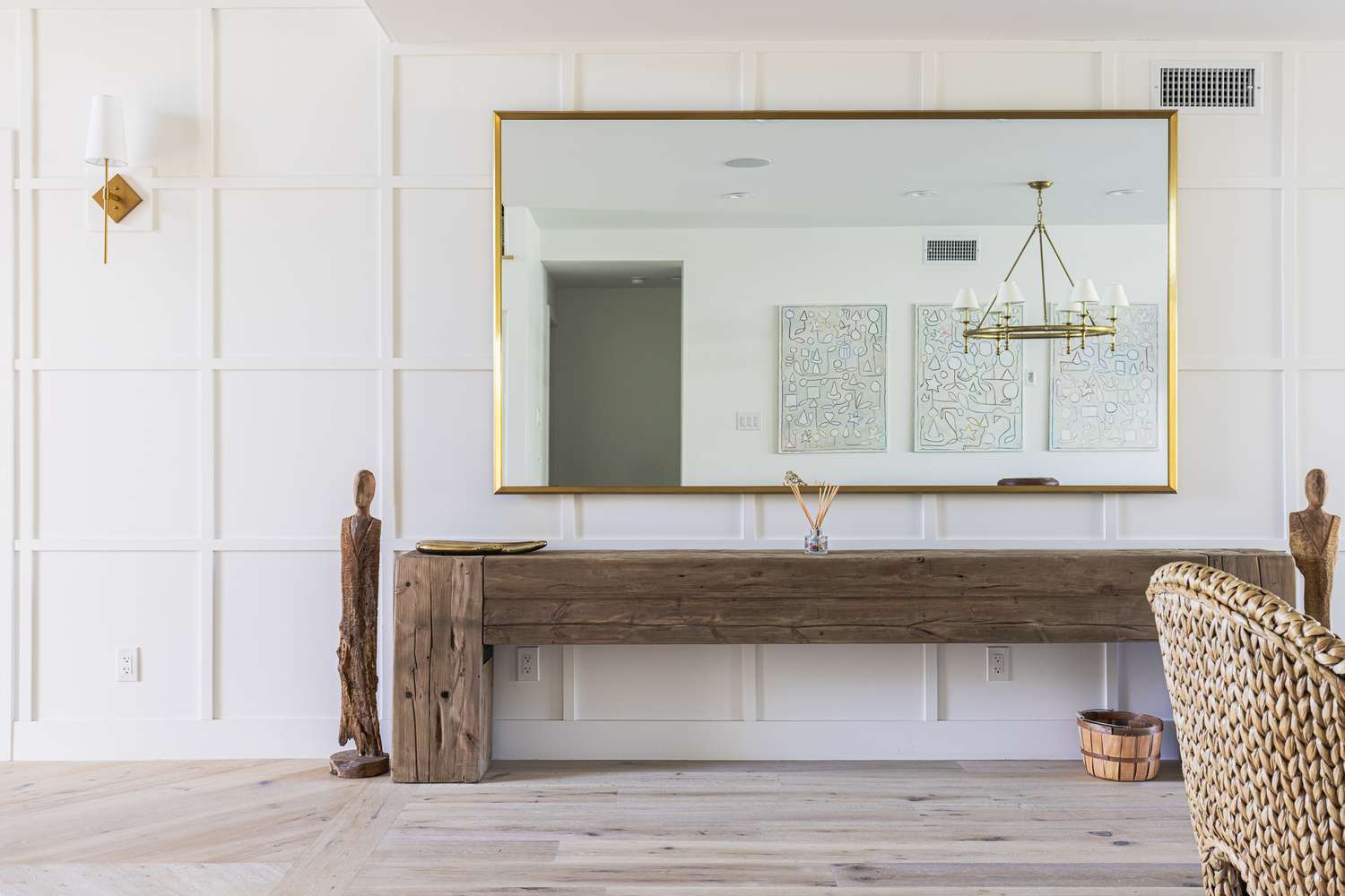 Espejo rectangular grande colgado sobre mesa auxiliar larga de madera con decoración mínima