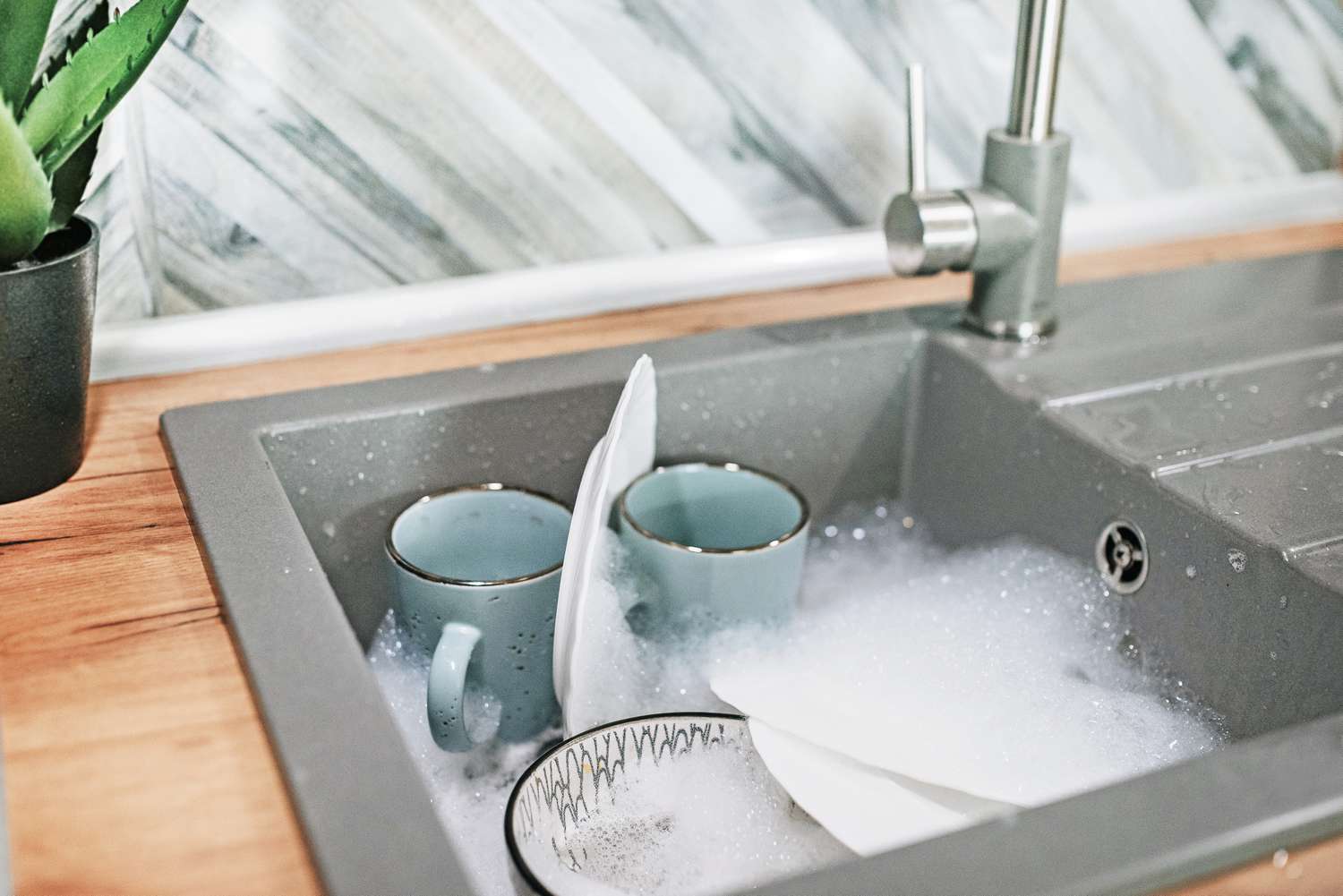 Vaisselle trempée dans l'évier de la cuisine avec de l'eau savonneuse