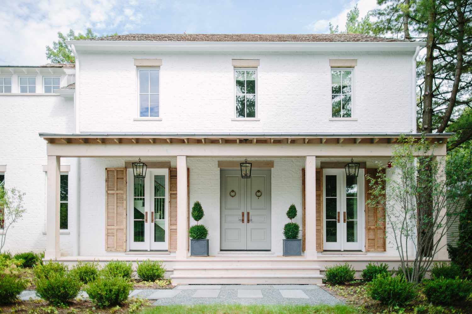 Ein weißes Haus mit einer salbeifarbenen Eingangstür im französischen Stil