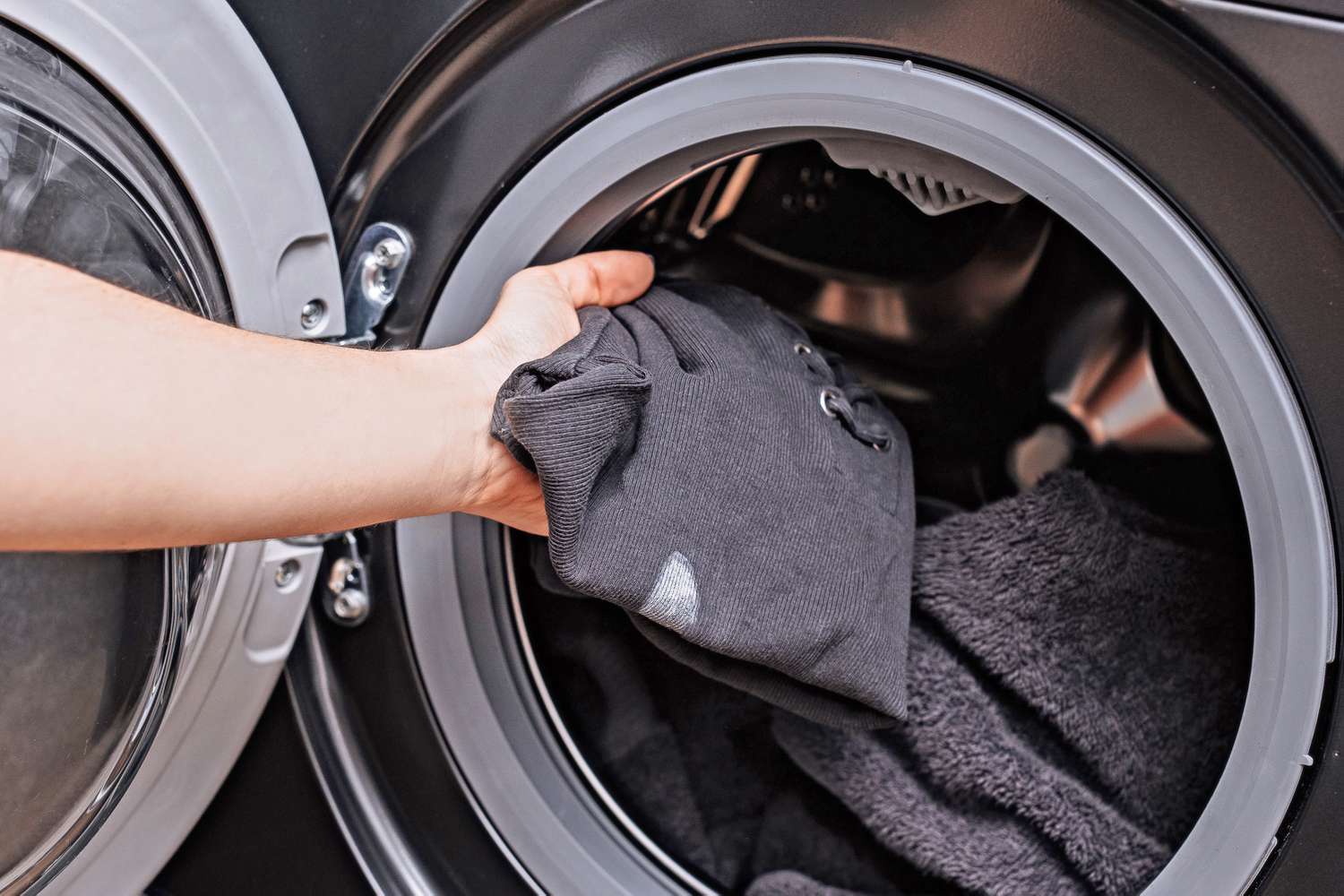 Camisa preta com mancha de corretivo branco colocada na máquina de lavar com removedor de manchas