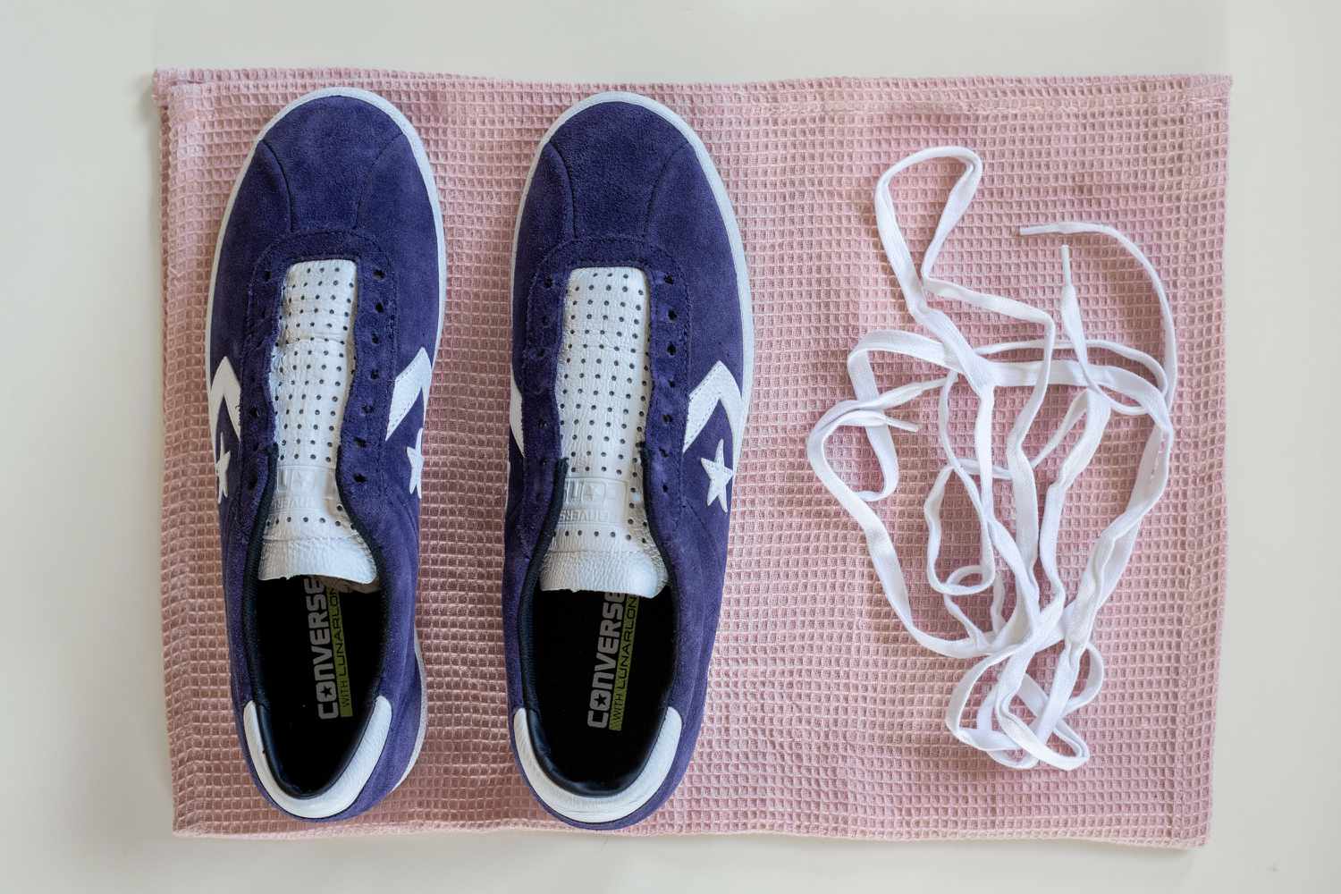 Weiße Schnürsenkel von blauen und weißen Wildleder-Sneakers von Converse entfernt