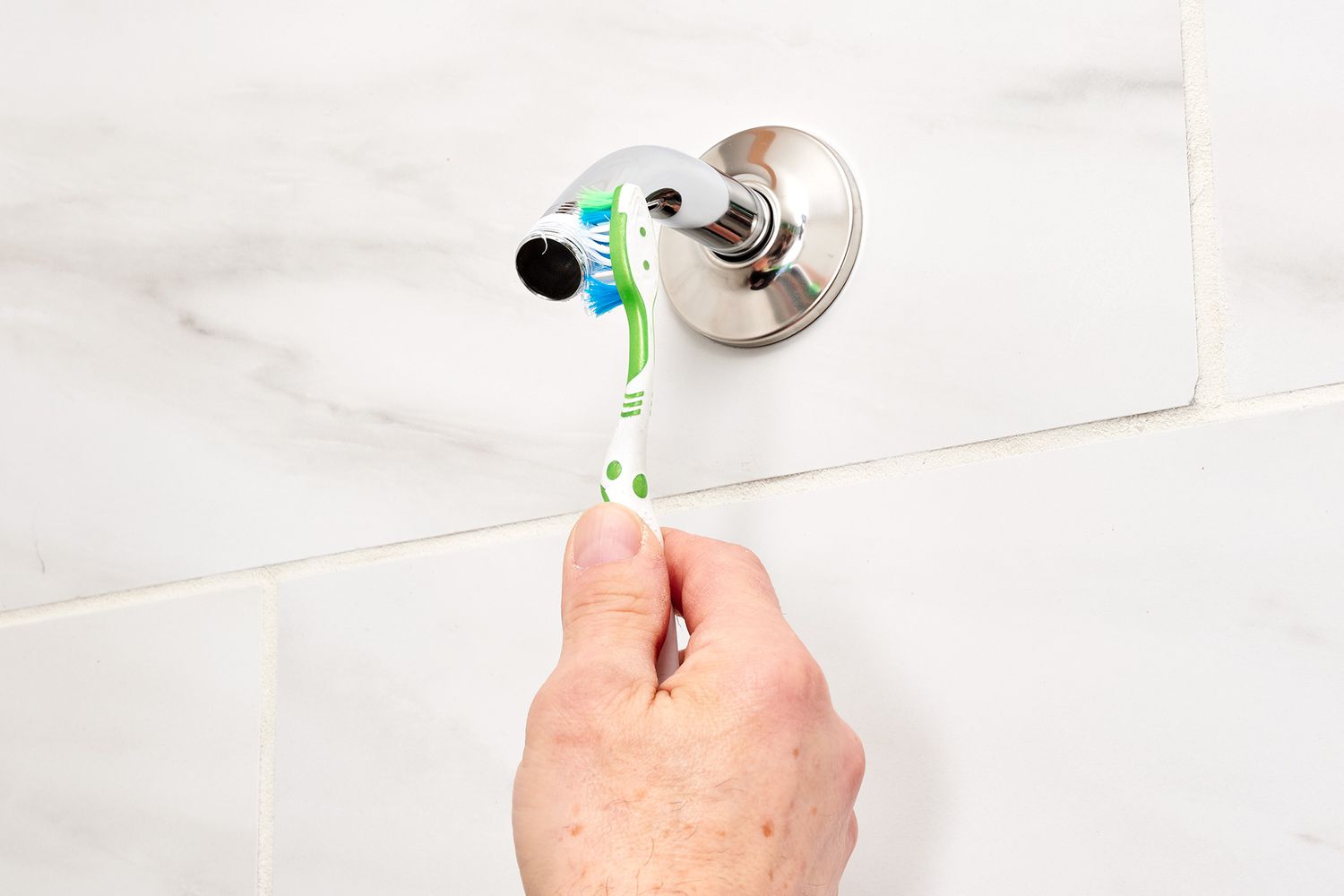 Old toothbrush scrubbing gunk off shower arm threads