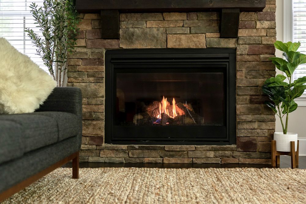 Ventless gas fireplace decorated with surrounding bricks, houseplants and couch