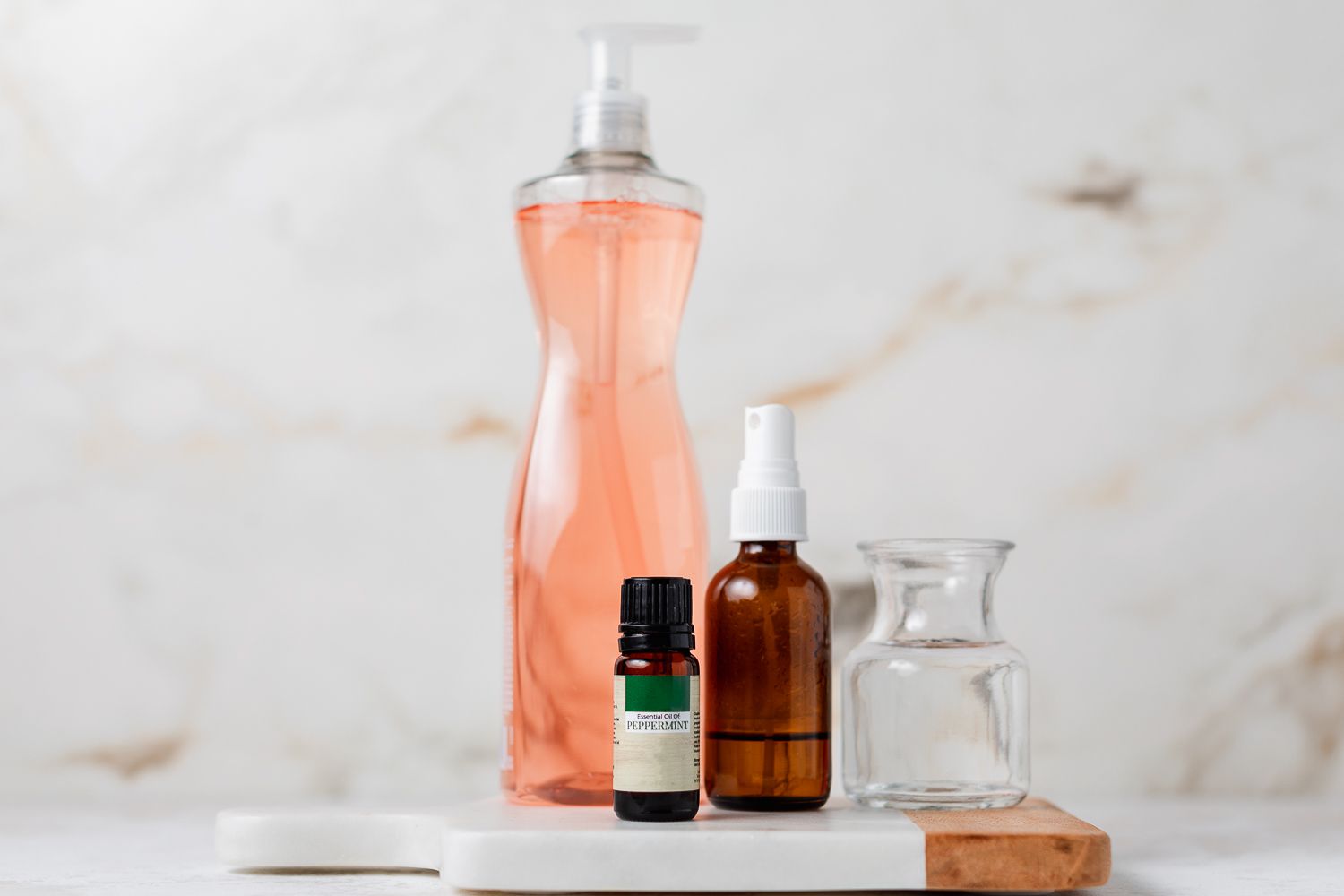 Aceite esencial de menta junto a botella de spray y lavavajillas rosa