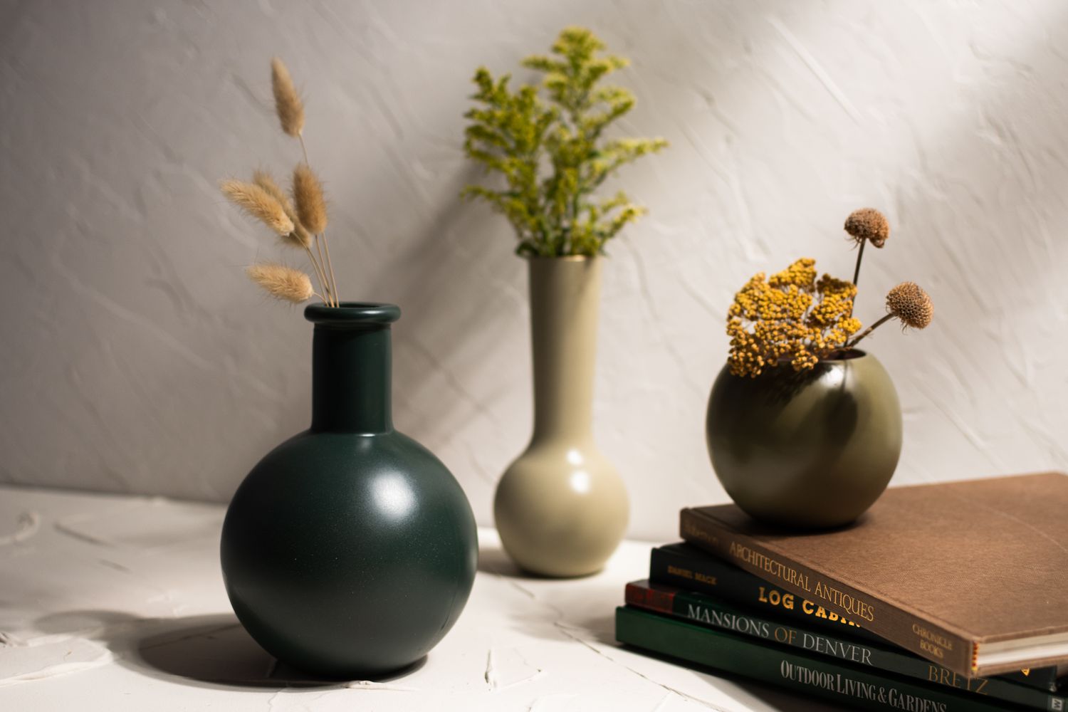 Vases en verre peints avec petits bouquets de fleurs empilés sur des livres closeup