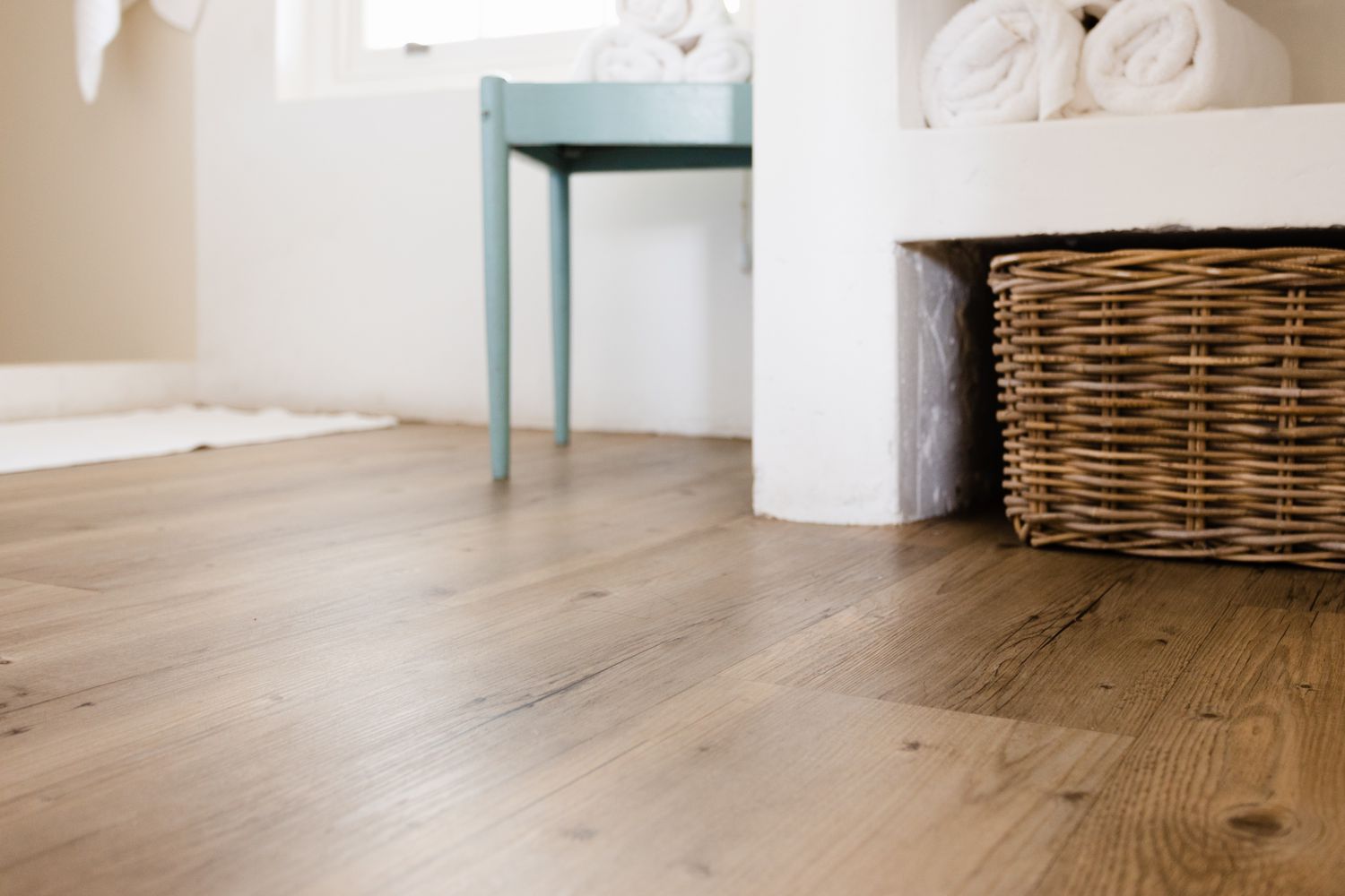 Plancher en vinyle avec panier en osier et table d'appoint bleue avec serviettes roulées blanches 