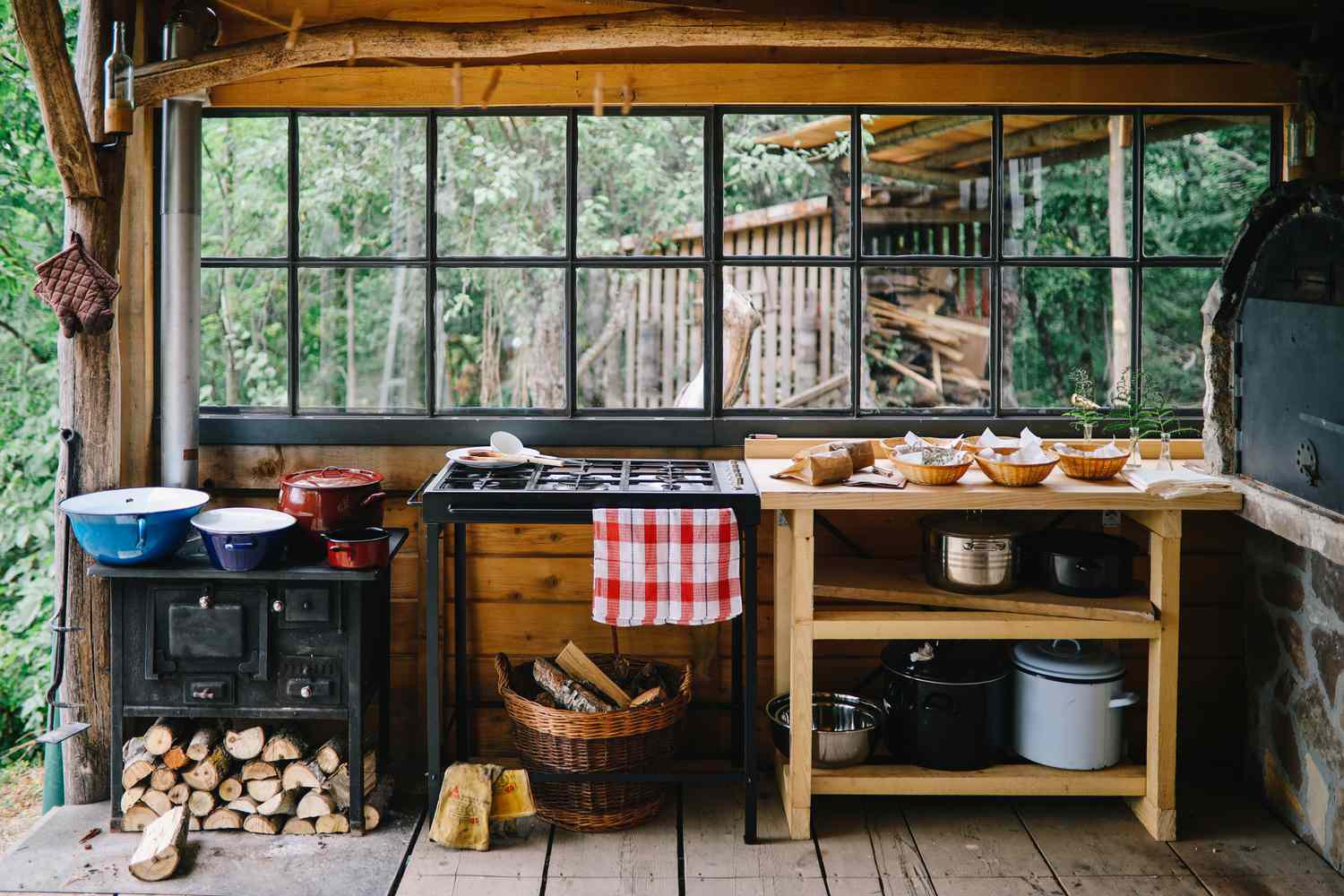 Cozinha de verão com um fogão a lenha e vários equipamentos e acessórios de cozinha