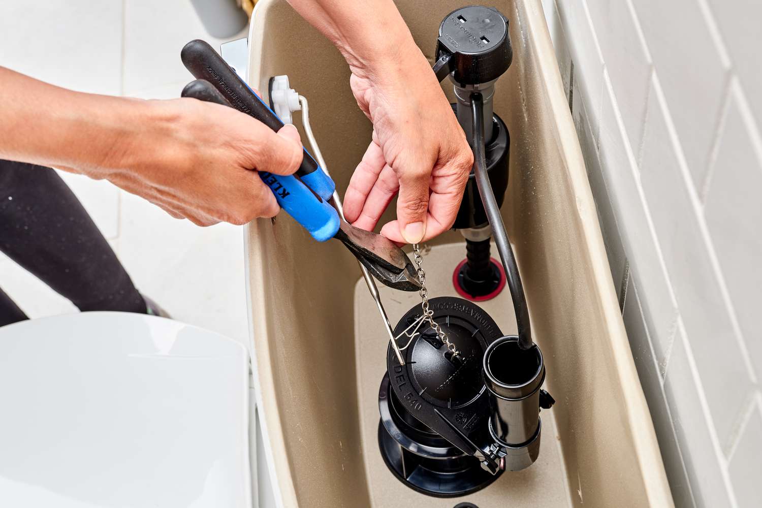 Flapper chain trimmed with cutting pliers inside toilet tank