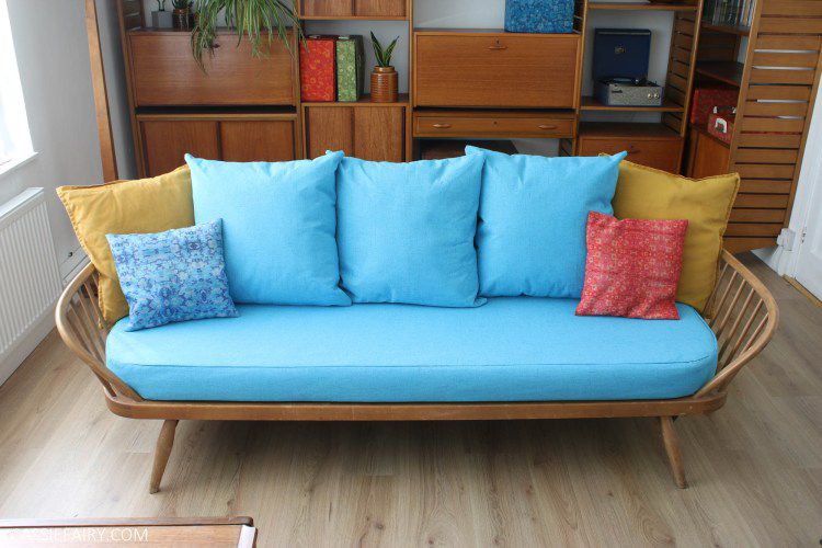 Un divertido sofá azul con muchos cojines de colores.