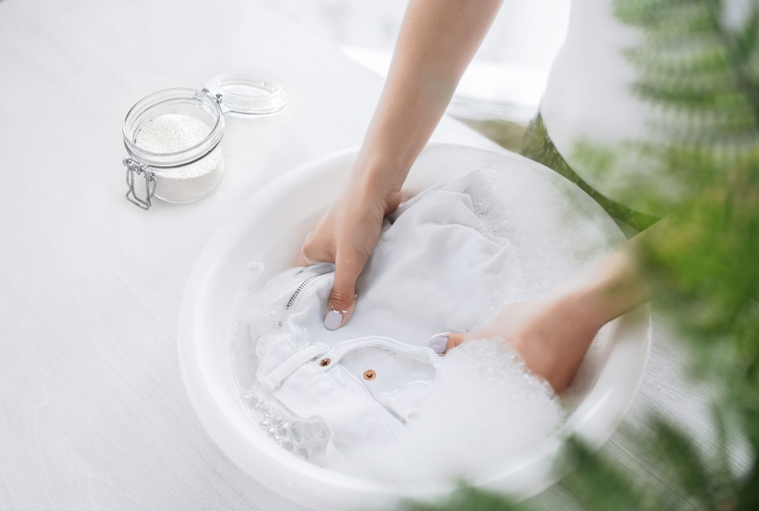 White jeans soaking in cool water with oxygen based bleach in glass container