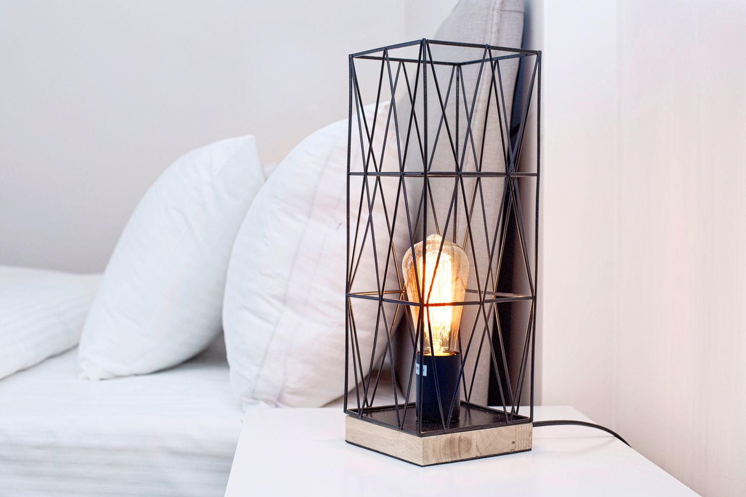 Close-Up Of Illuminated Lamp On Night Table By Bed At Home