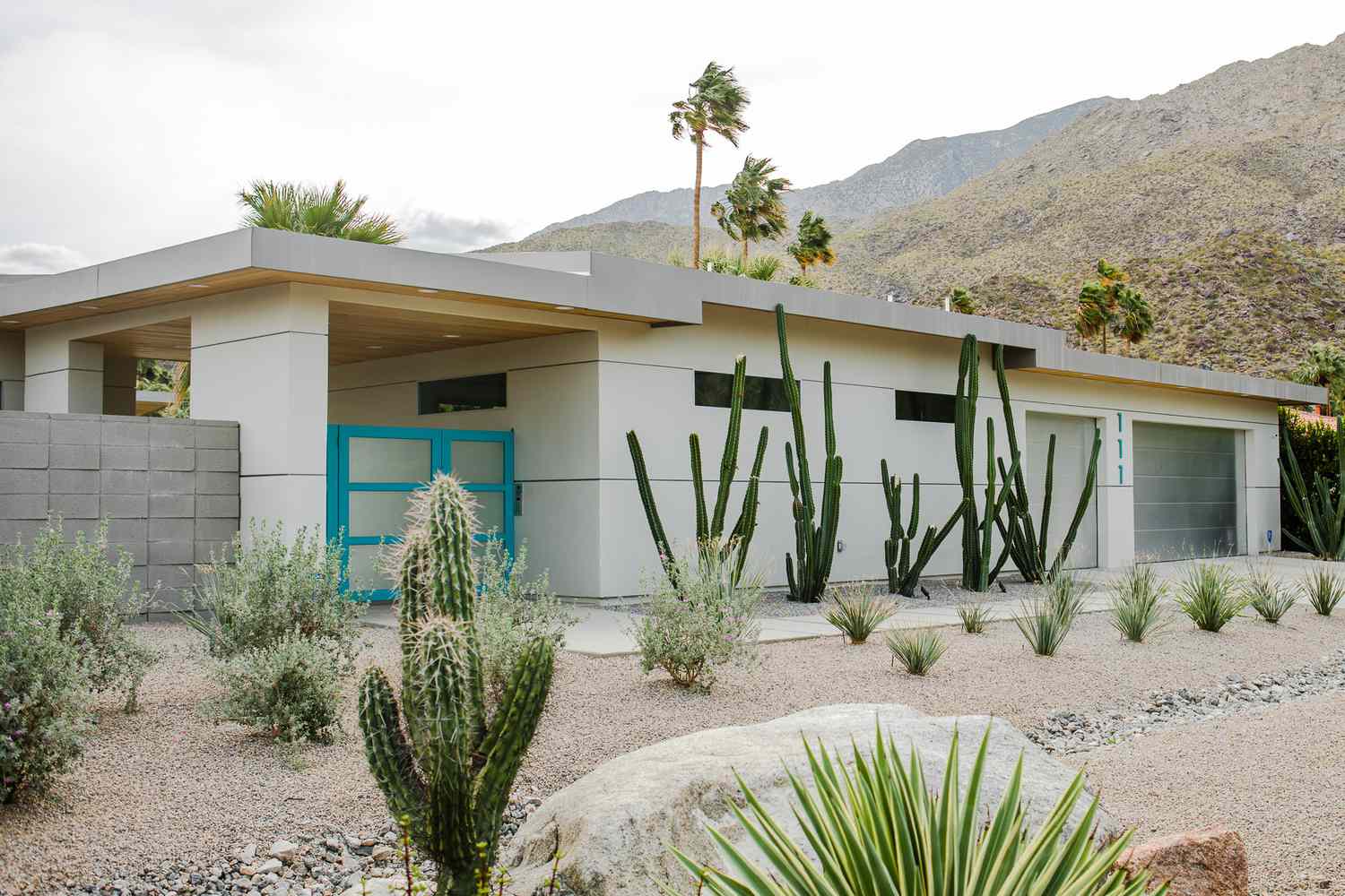 Weißes modernes Haus in wüstenartiger Landschaft mit hellblauem Garagentor