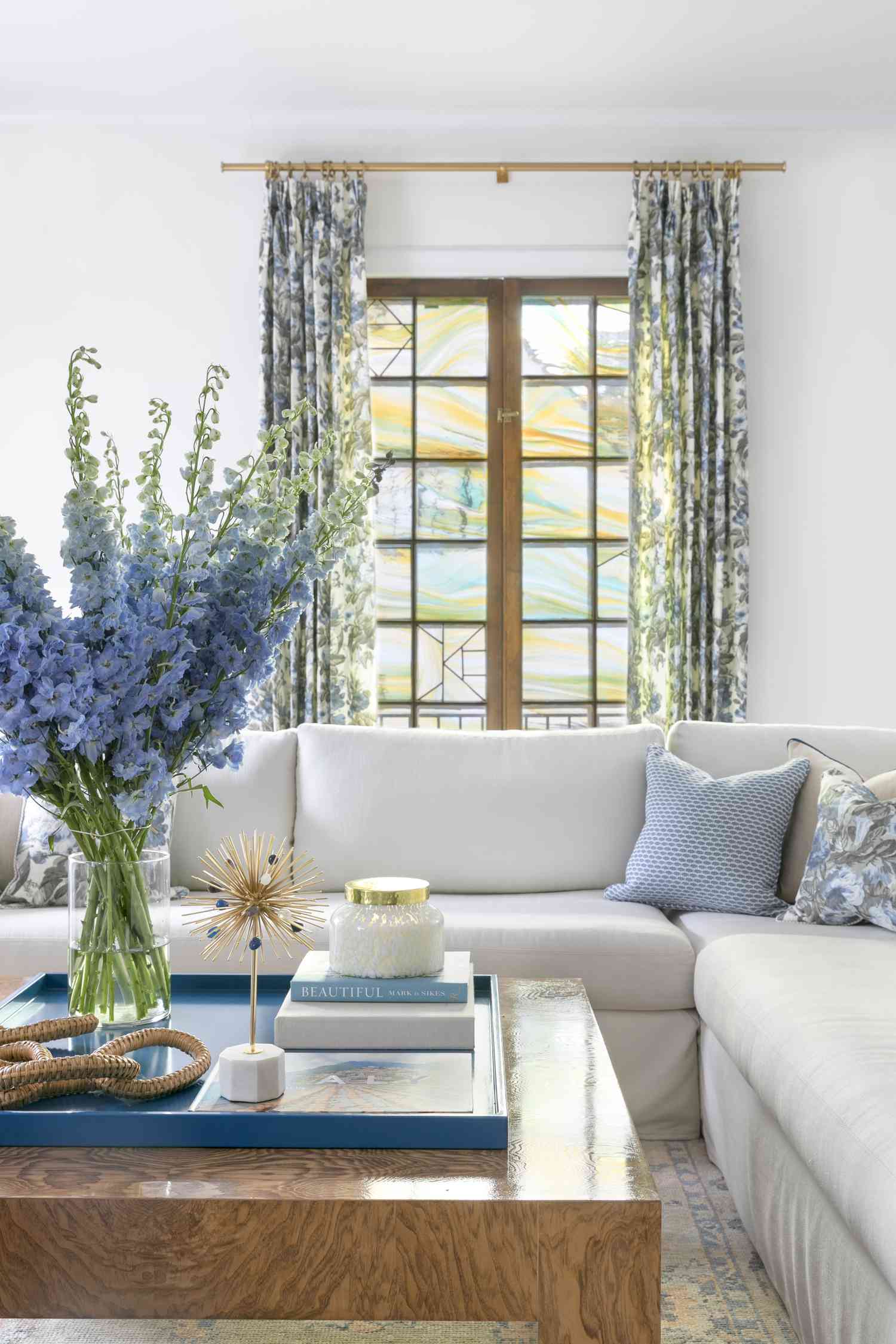 Gemütliches Wohnzimmer im Landhausstil mit großem Blumenarrangement auf dem Tisch.