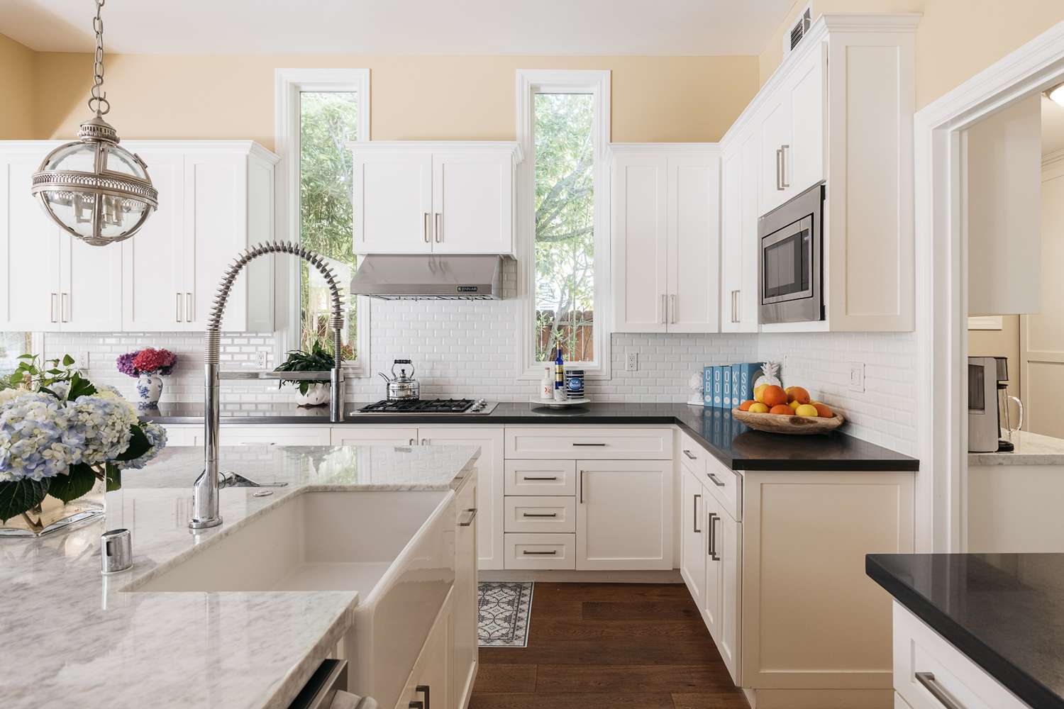 Cozinha de cor neutra com armários brancos e bancadas pretas