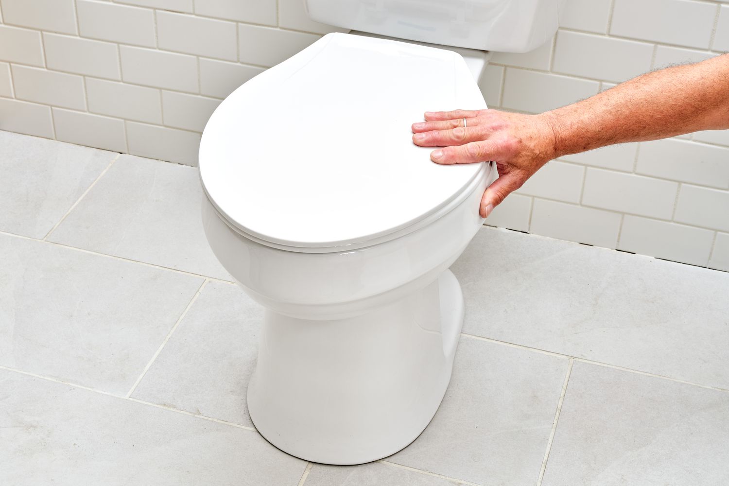 Vaso sanitário branco sendo mexido com a mão