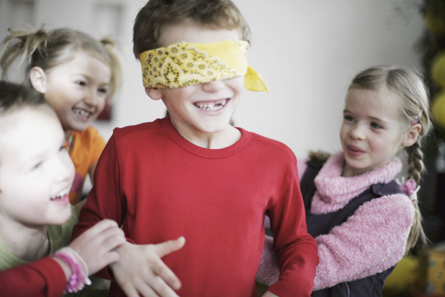one blindfolded kid with three others laughing nearby
