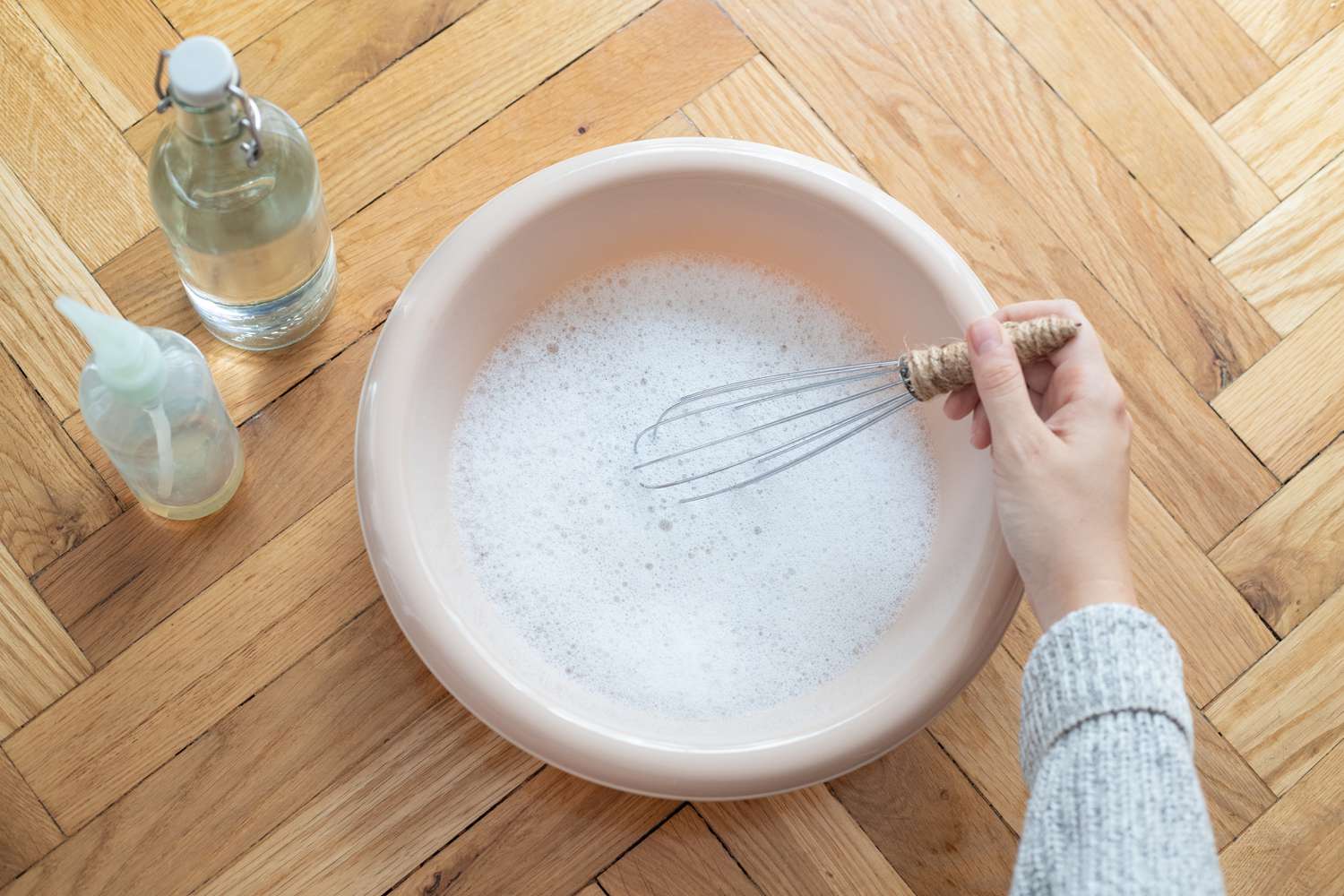 Solução de limpeza misturada com água e sabão líquido de lavar louça com um batedor em uma tigela grande