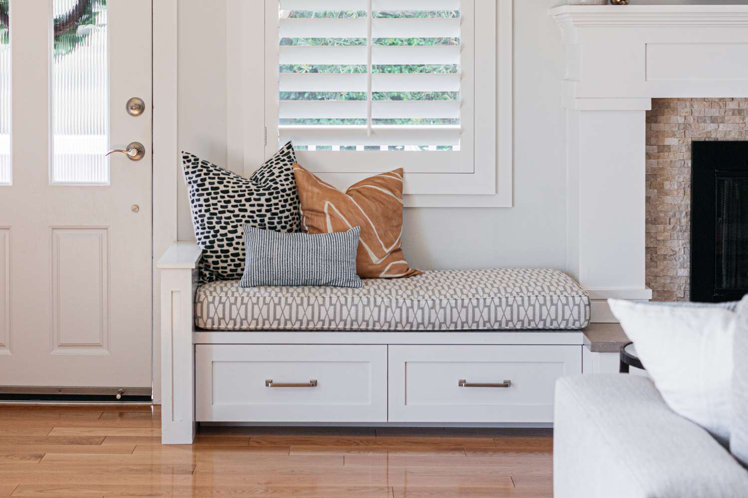 Window seat with white drawers and multiple patterned pillows and cushion