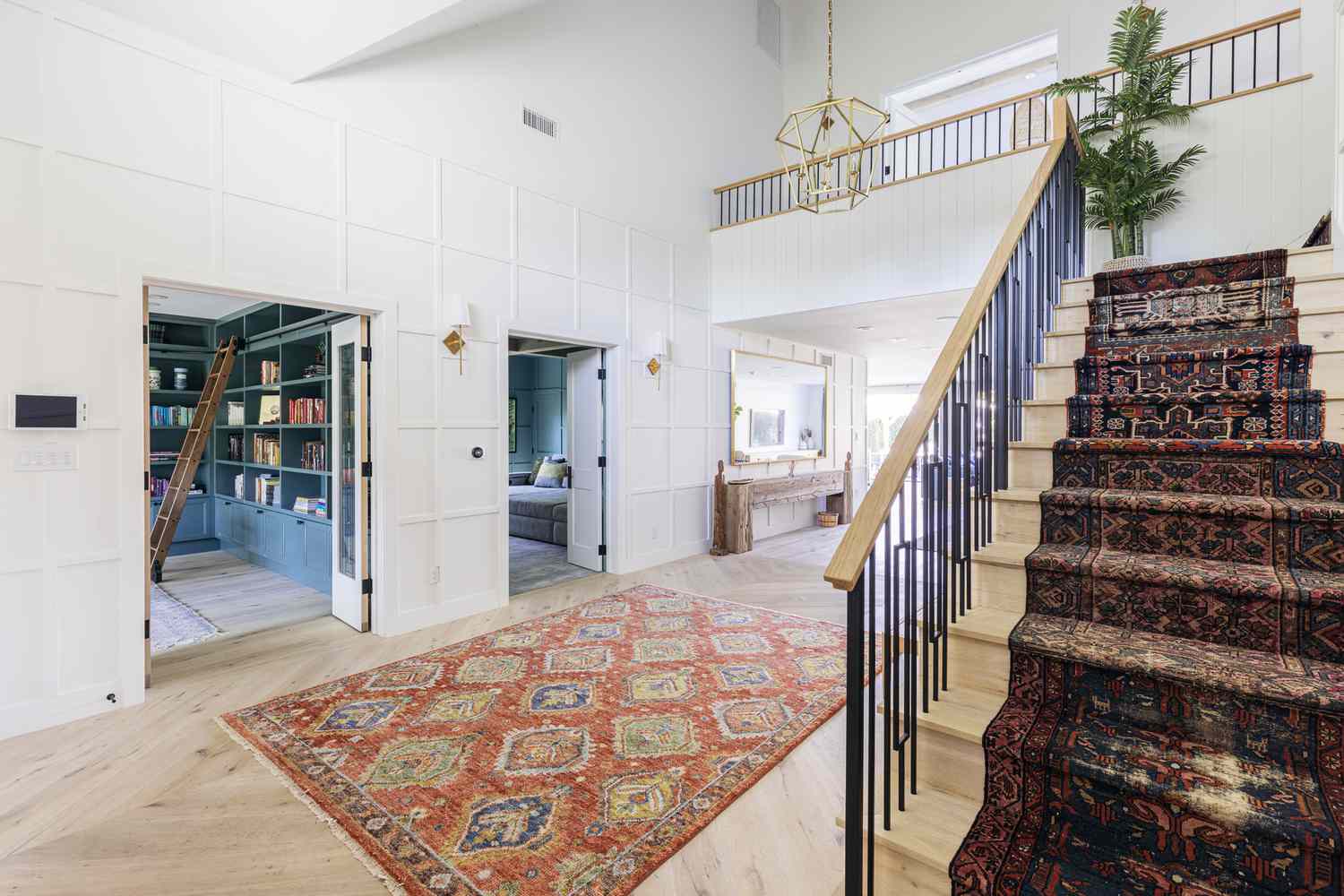 Entrada ampla decorada com tapete estampado no meio e na escada