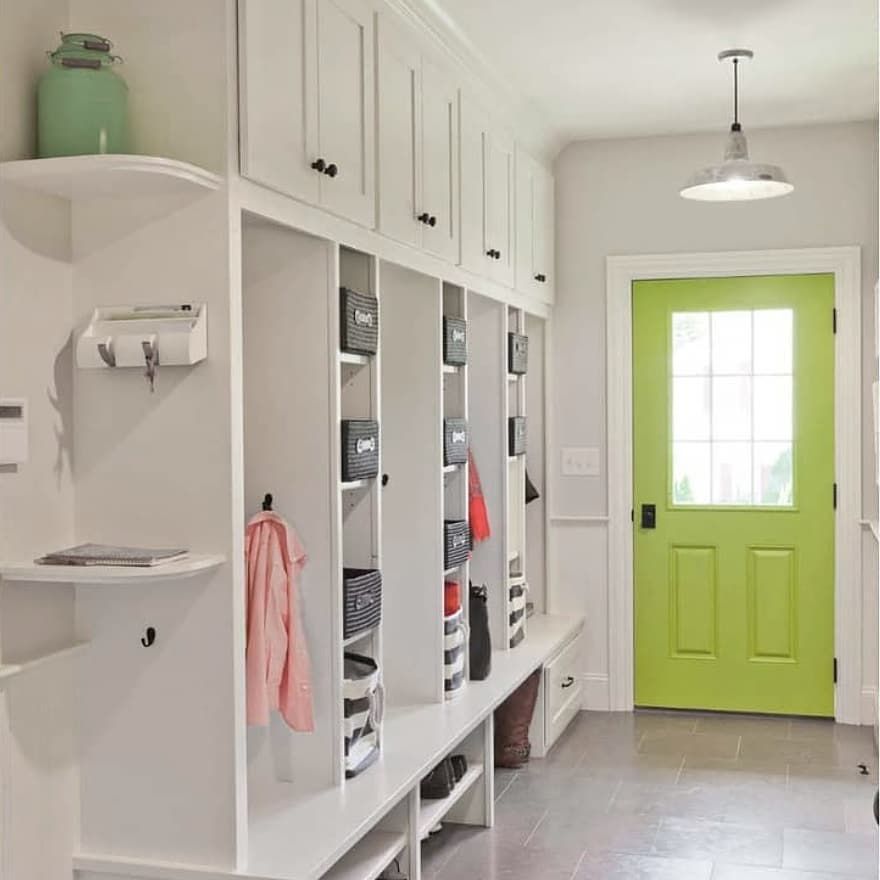 Eine Abstellkammer mit weißen Regalen und Ablagefächern und einer hellgrünen Tür.