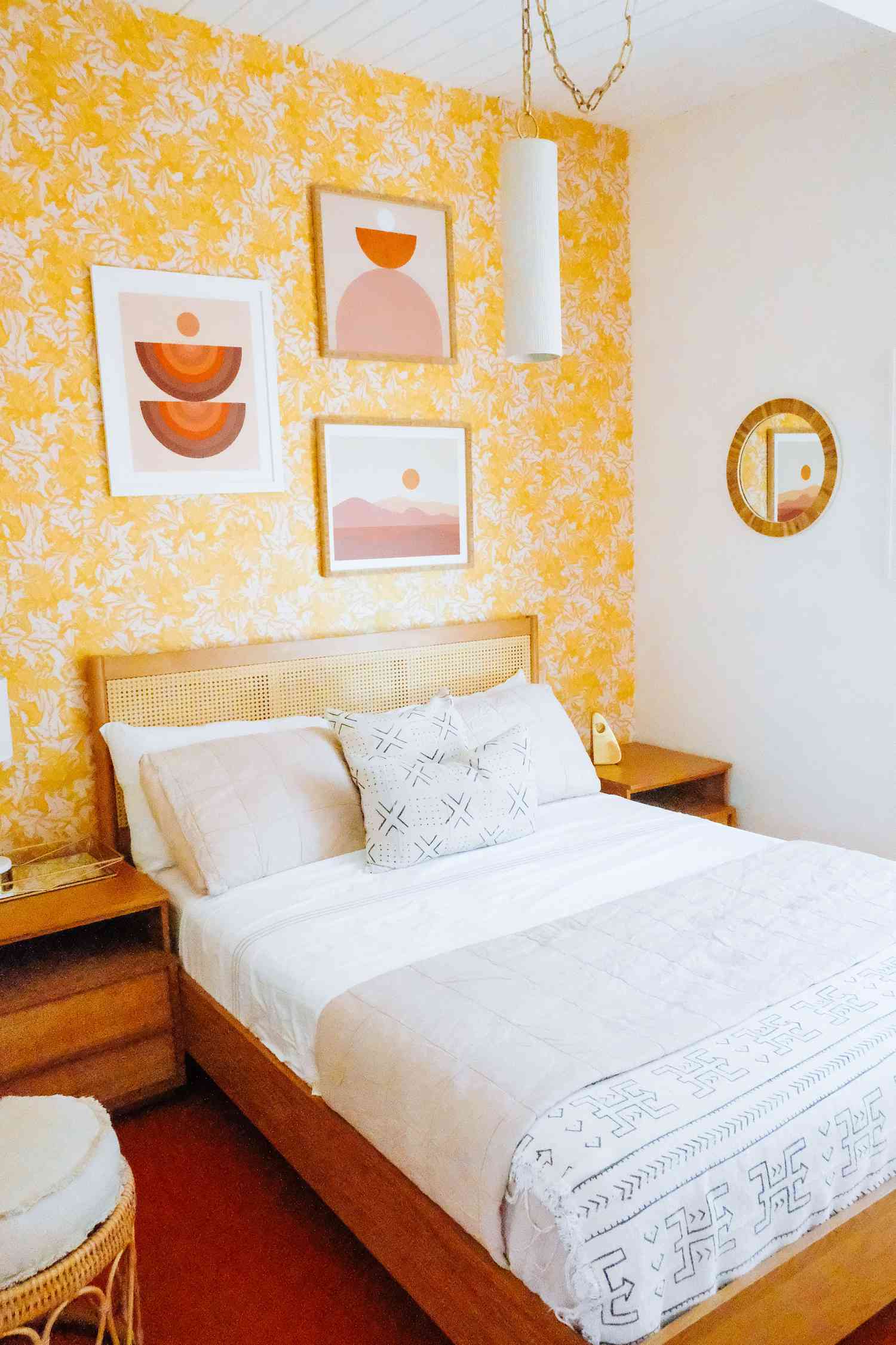 dormitorio con papel pintado amarillo floral, acentuado con tonos rojos y naranjas, muebles de mimbre y madera