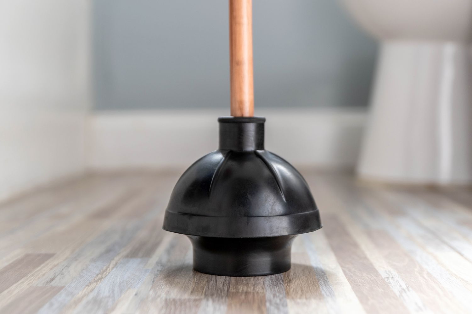 Black toilet plunger on bathroom floor