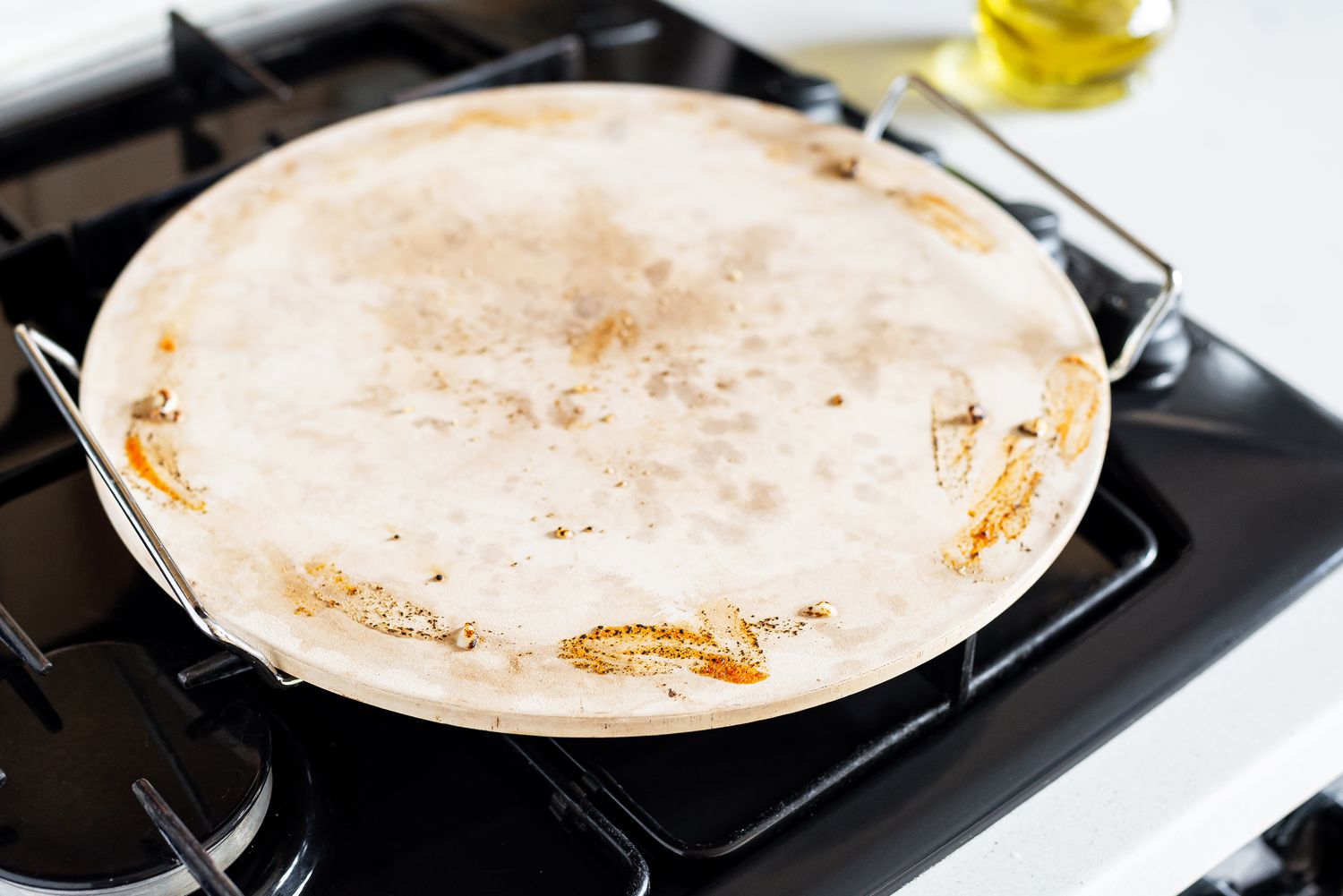 Benutzter Pizzastein auf der Herdplatte zum Abkühlen vor der Reinigung